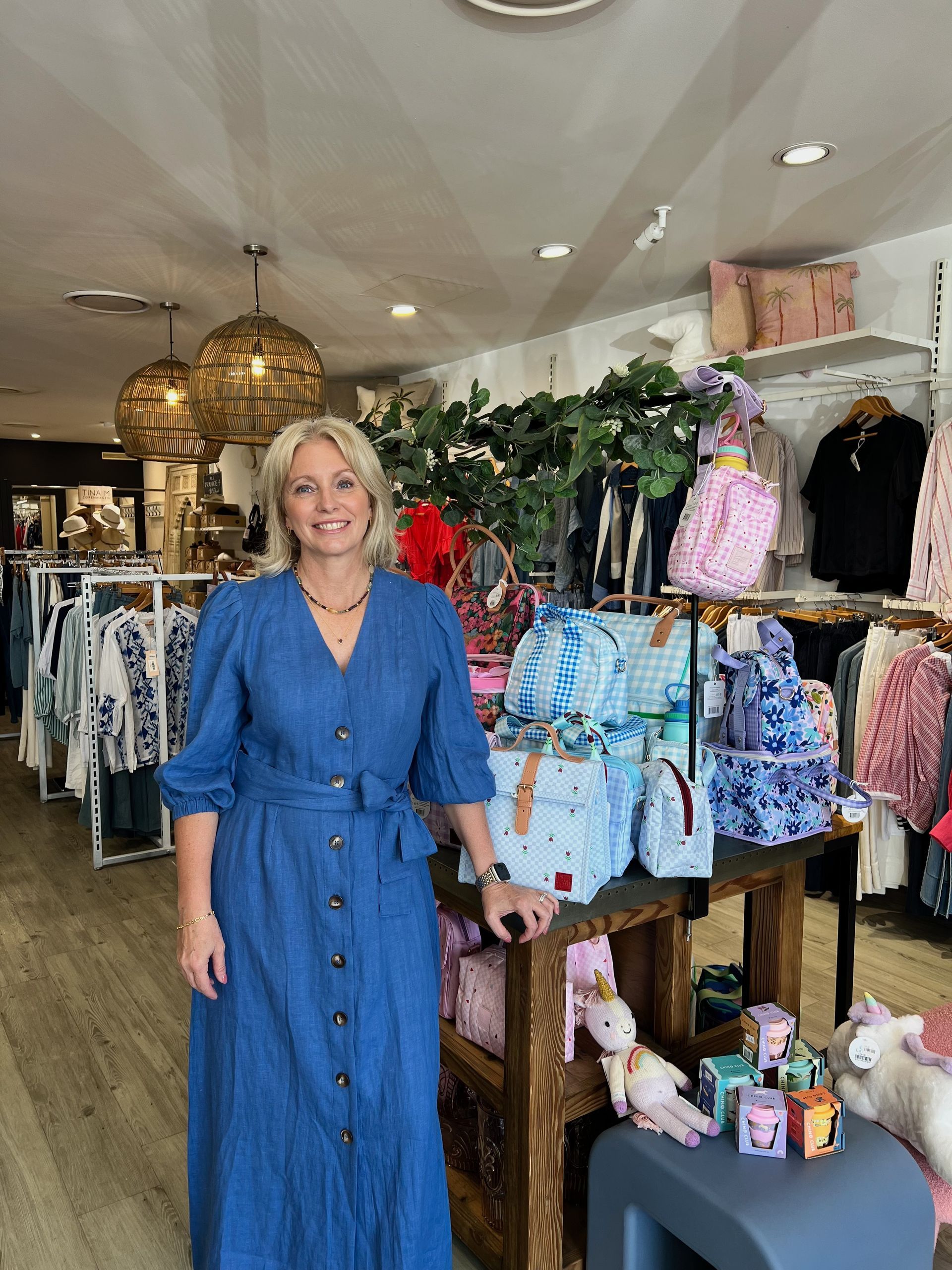 a Woman in a Red Dress is Standing in a Store Holding a Candle — Montaze In Erina, NSW