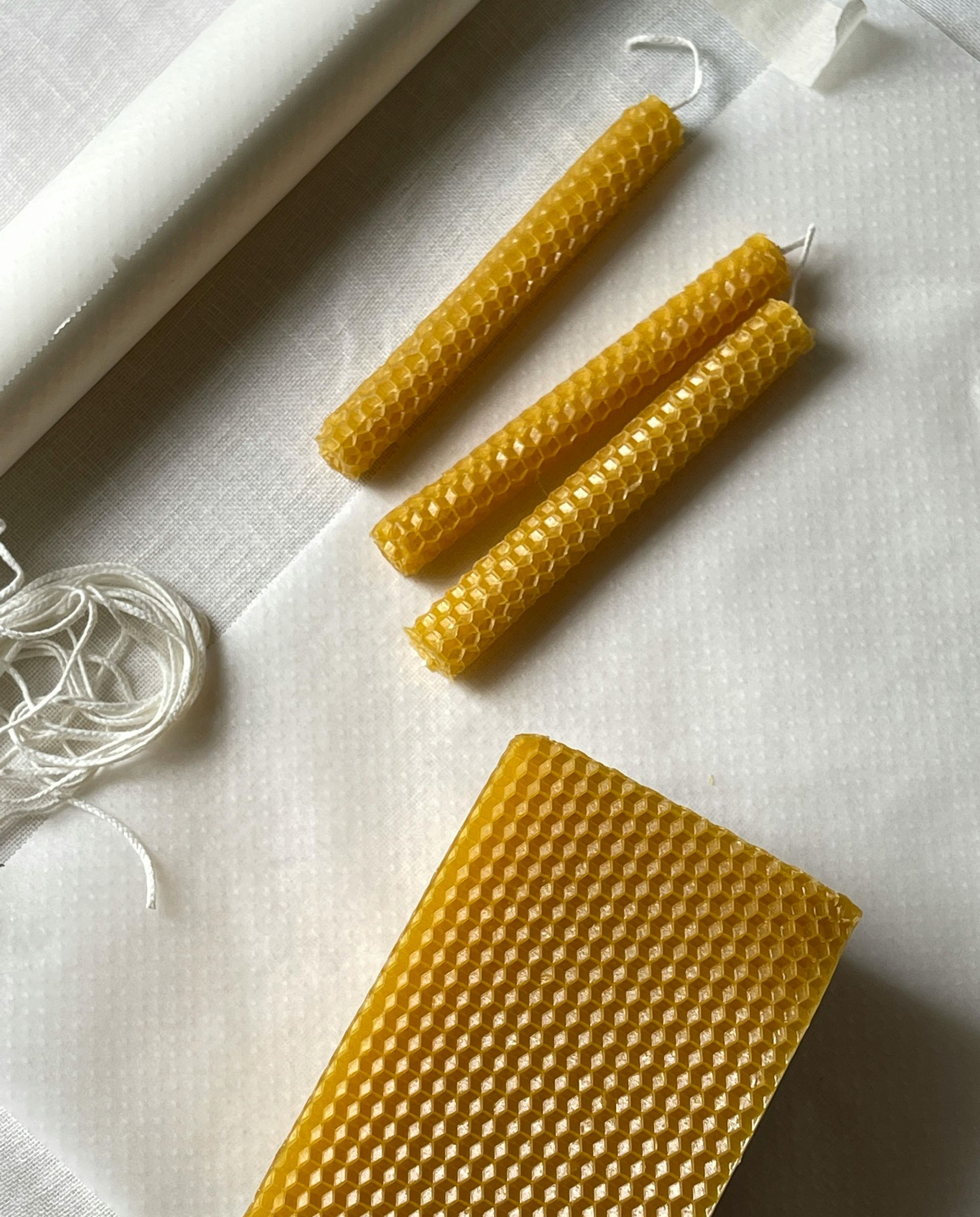 Beeswax candle making supplies: rolls of wax, wicks, and rolled candles.