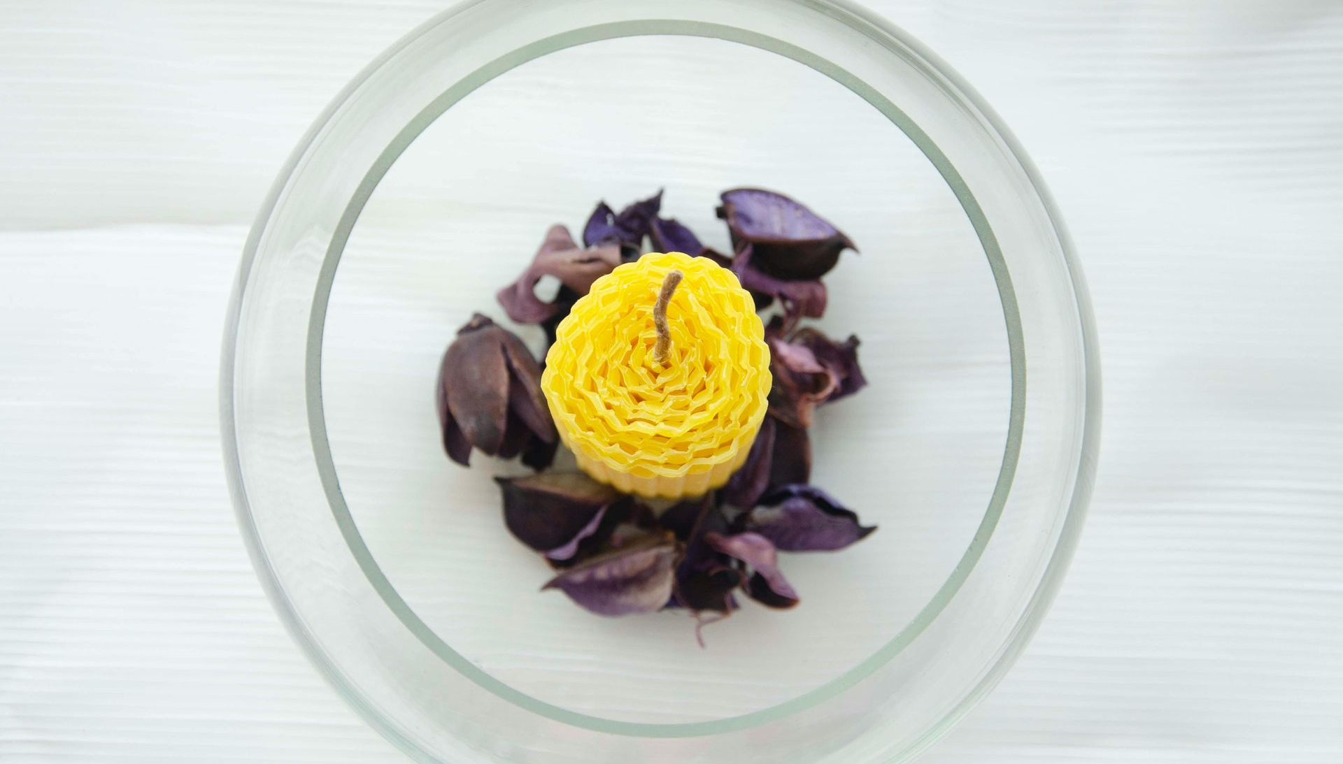 Glass bowl with yellow floral centerpiece and purple petals.