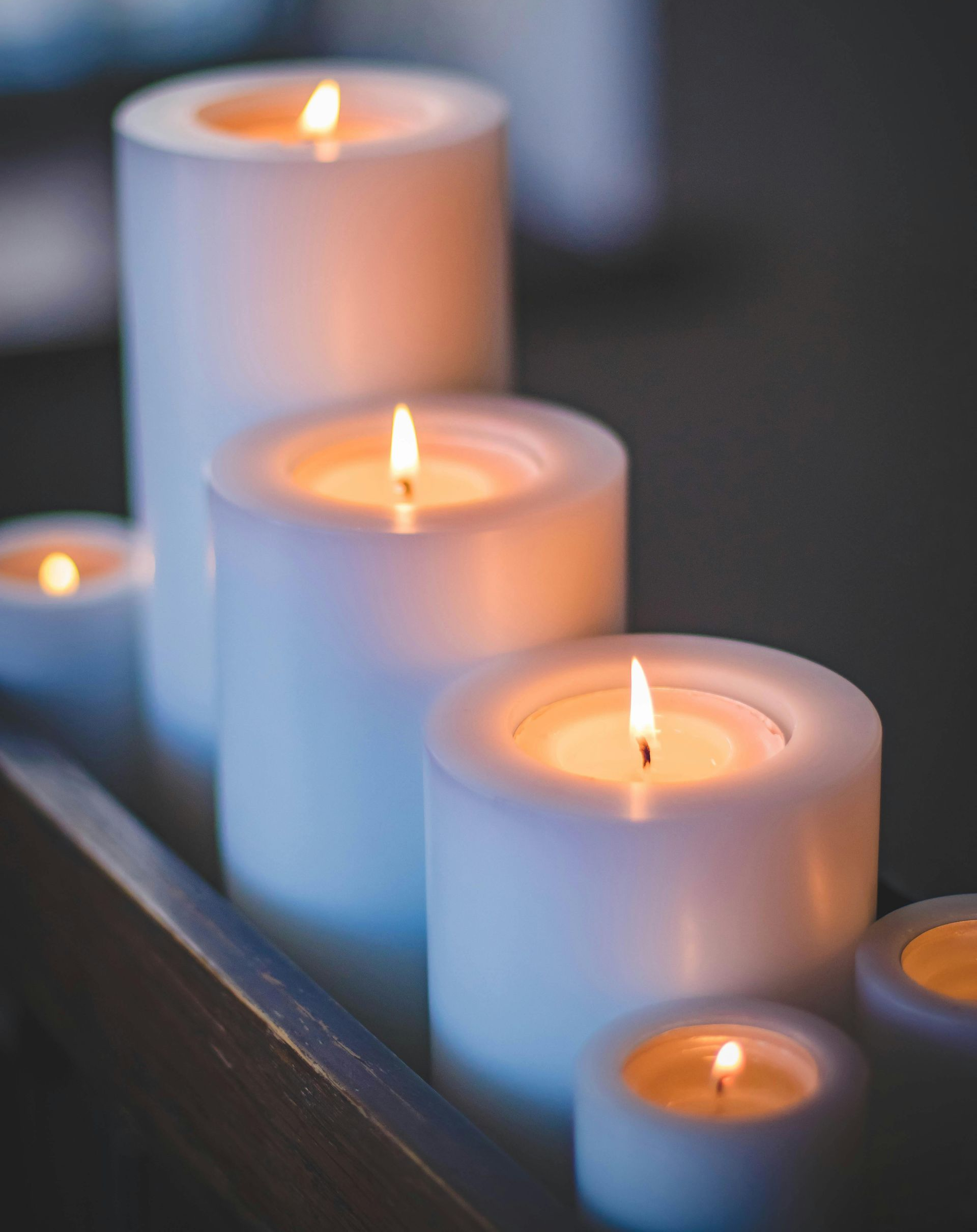 Burning white pillar candles in a row, casting a warm glow.