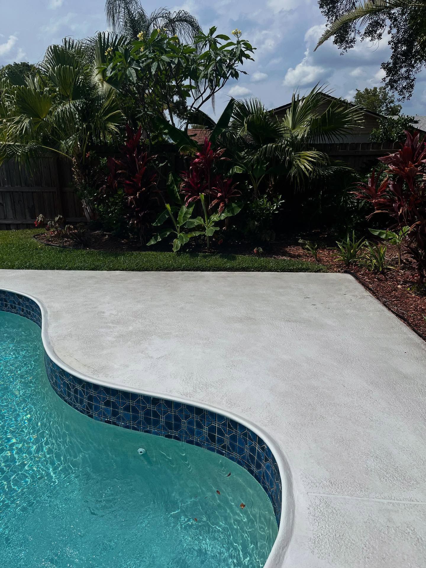 A swimming pool with a curved edge and a concrete deck