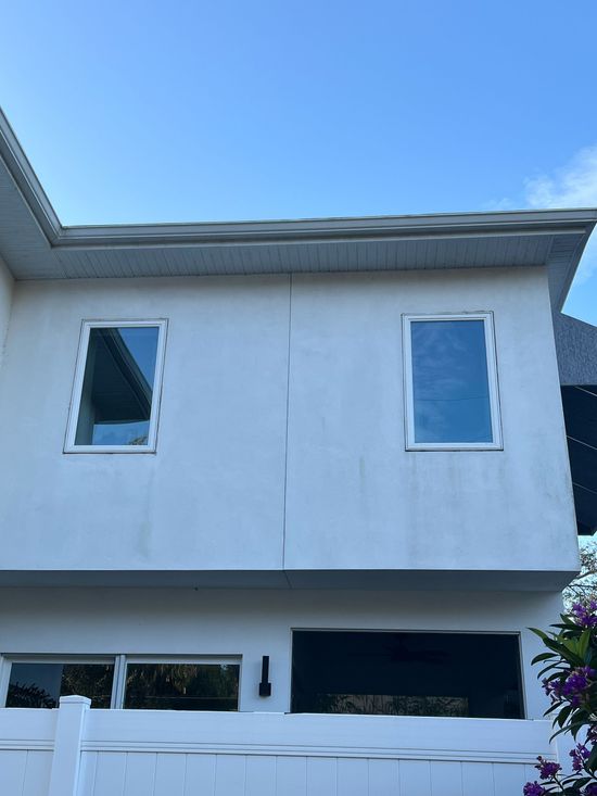 A white house with two windows and a blue sky in the background.