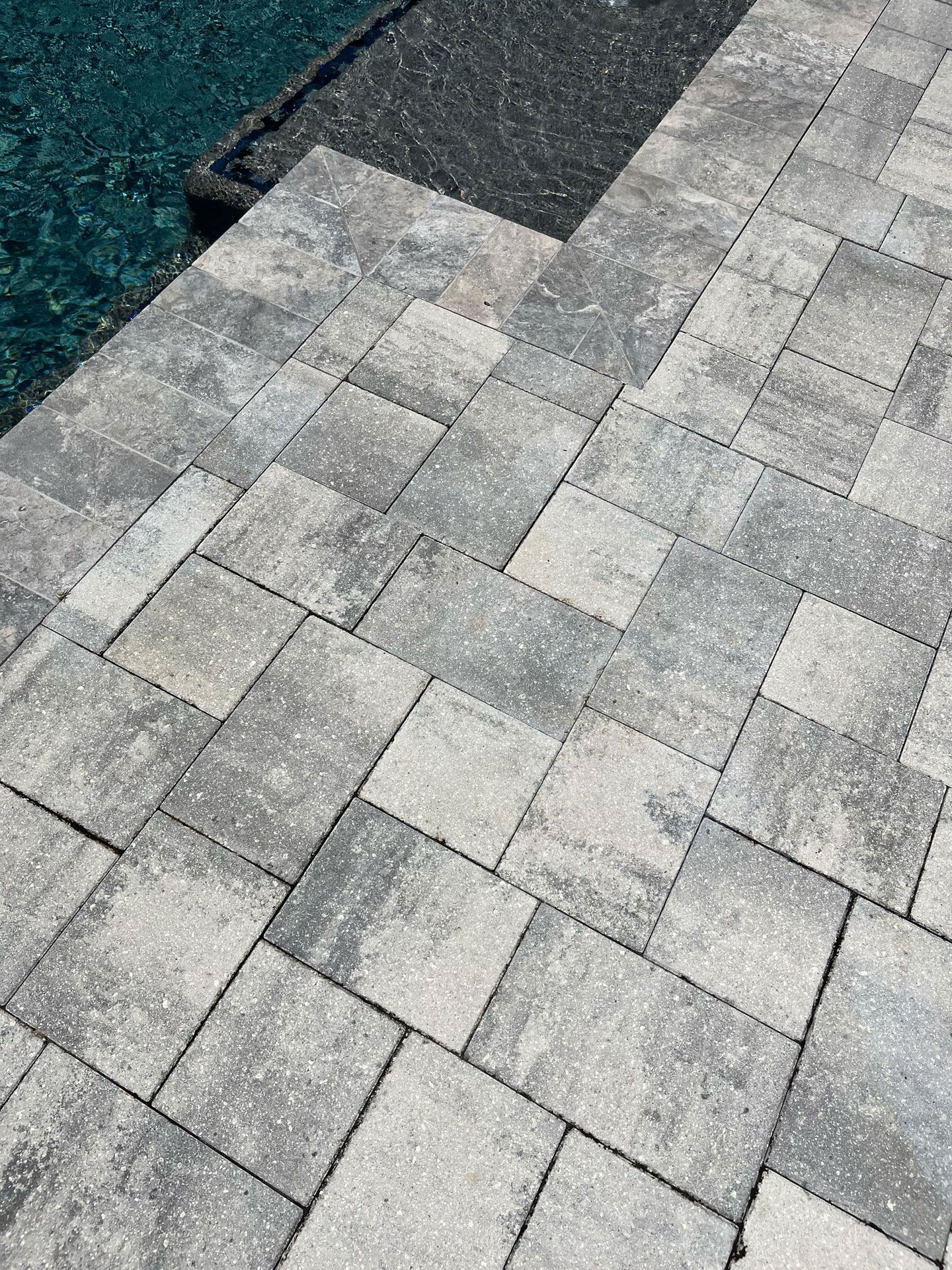 A close up of a brick walkway next to a pool.