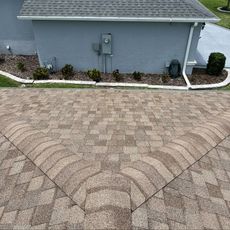 A brick driveway leading to a house with a roof.
