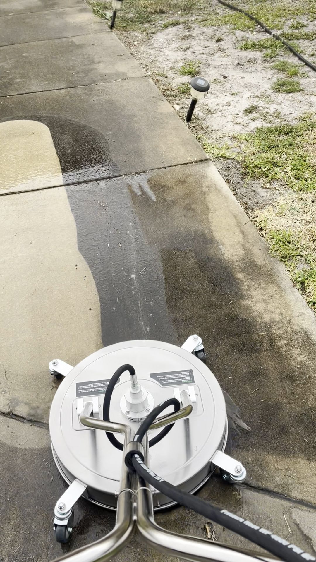A machine is cleaning a sidewalk with a hose attached to it.