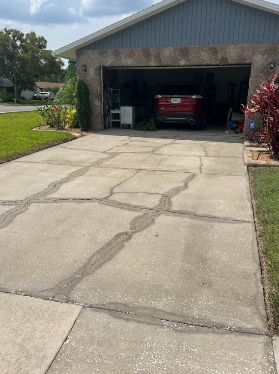A red car is parked in a garage next to a driveway.