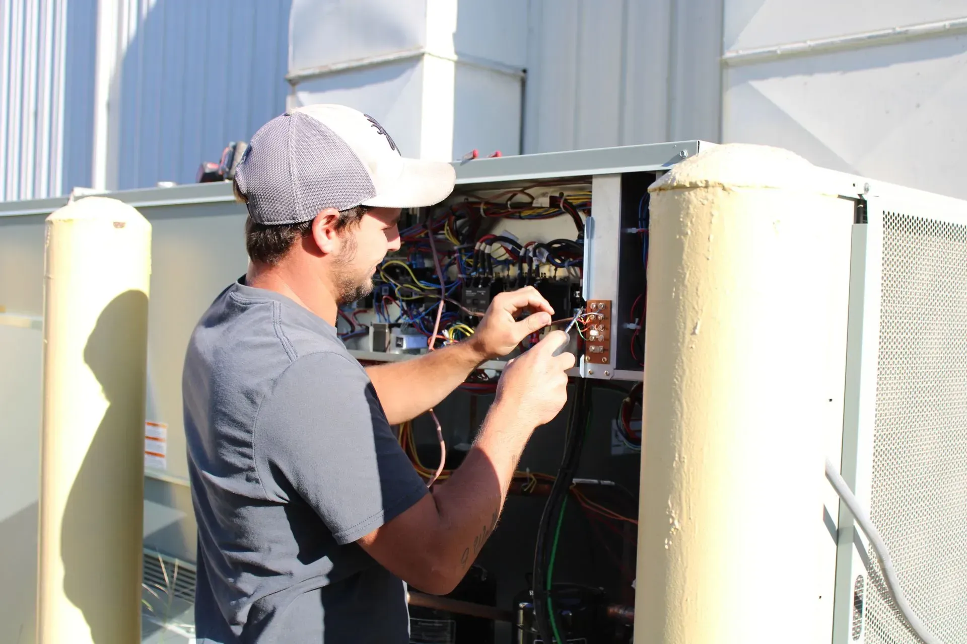 A man is working on an air conditioner outside of a building.