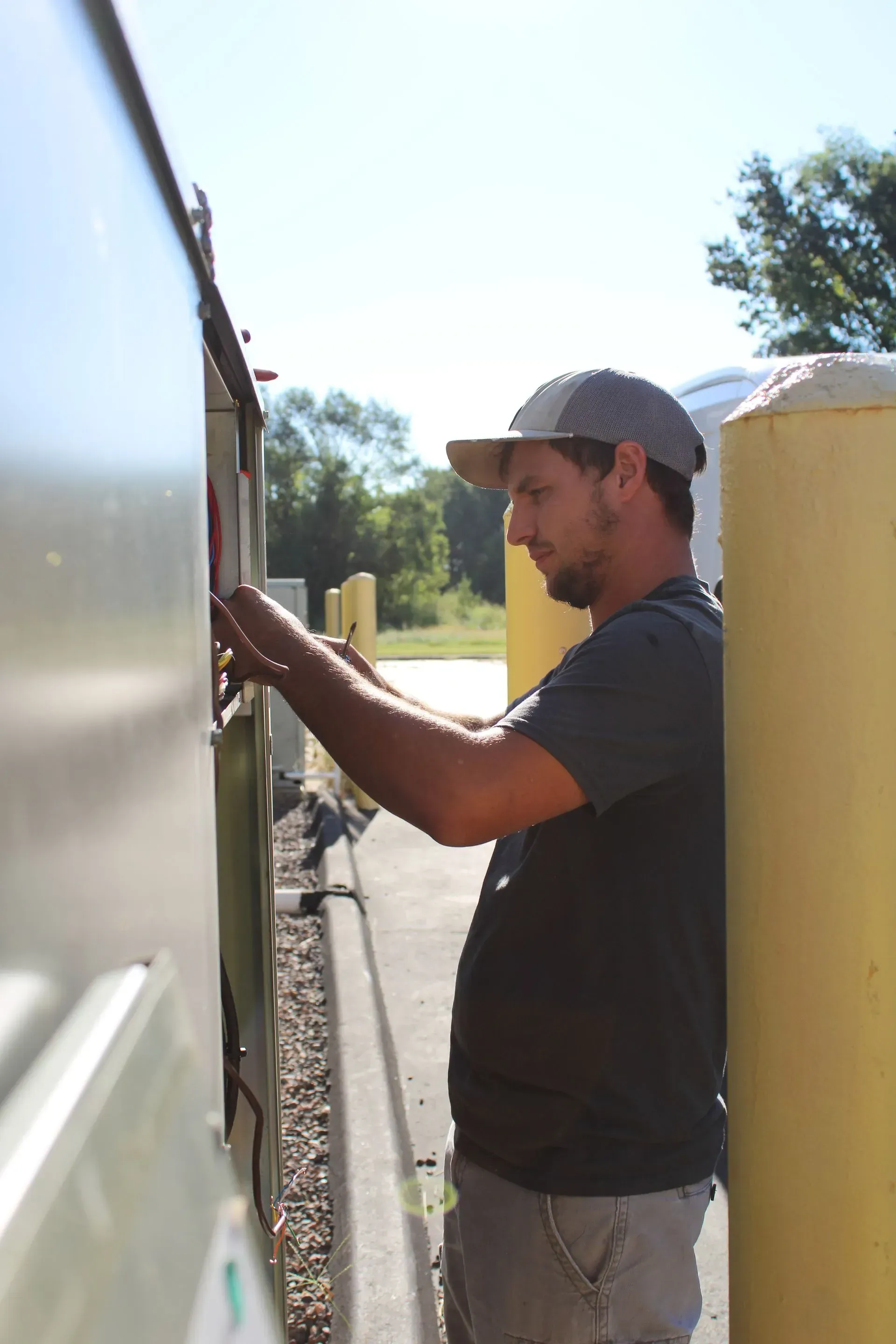 A man standing next to a yellow pole is working on something