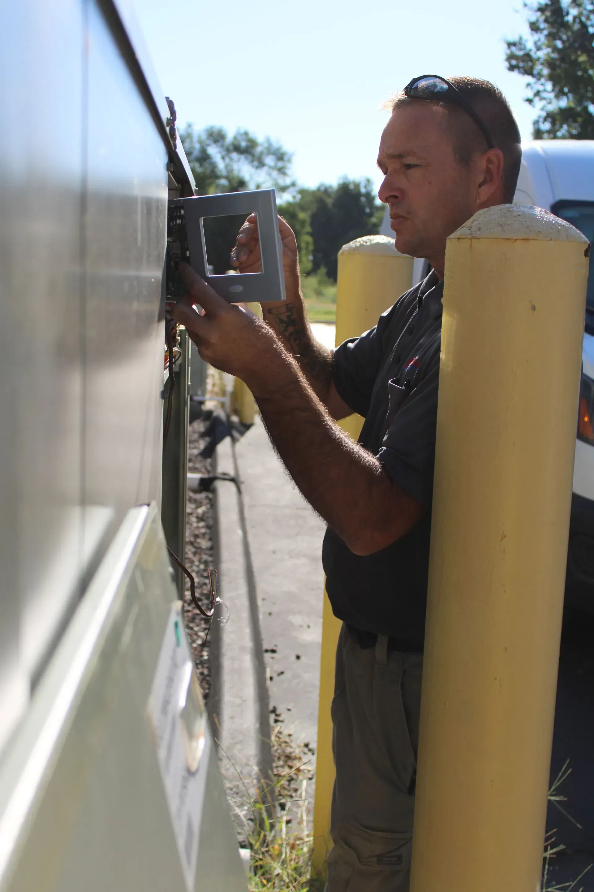 A man is standing next to a yellow pole looking at something on a wall.