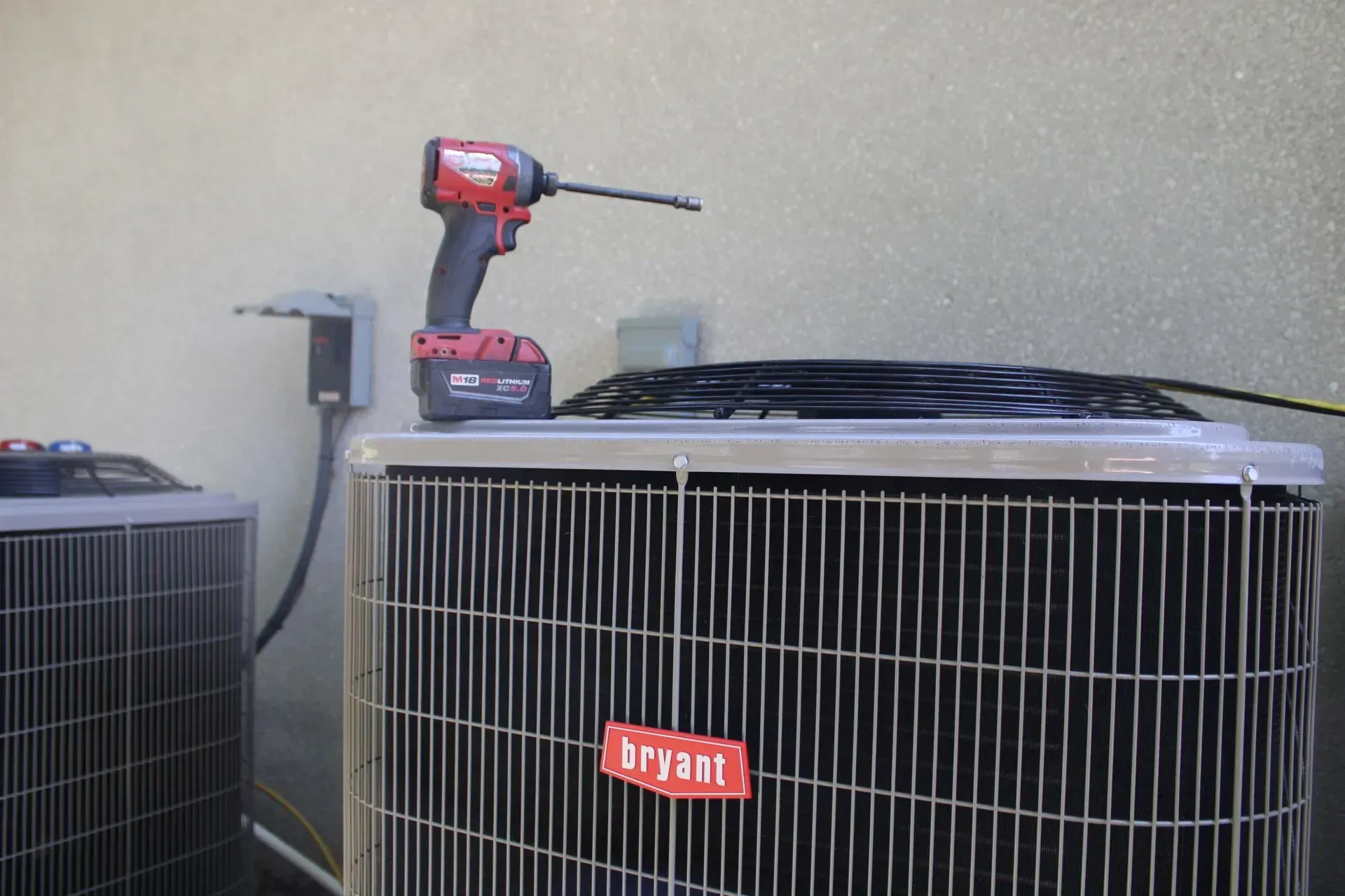 A drill is sitting on top of a bryant air conditioner.