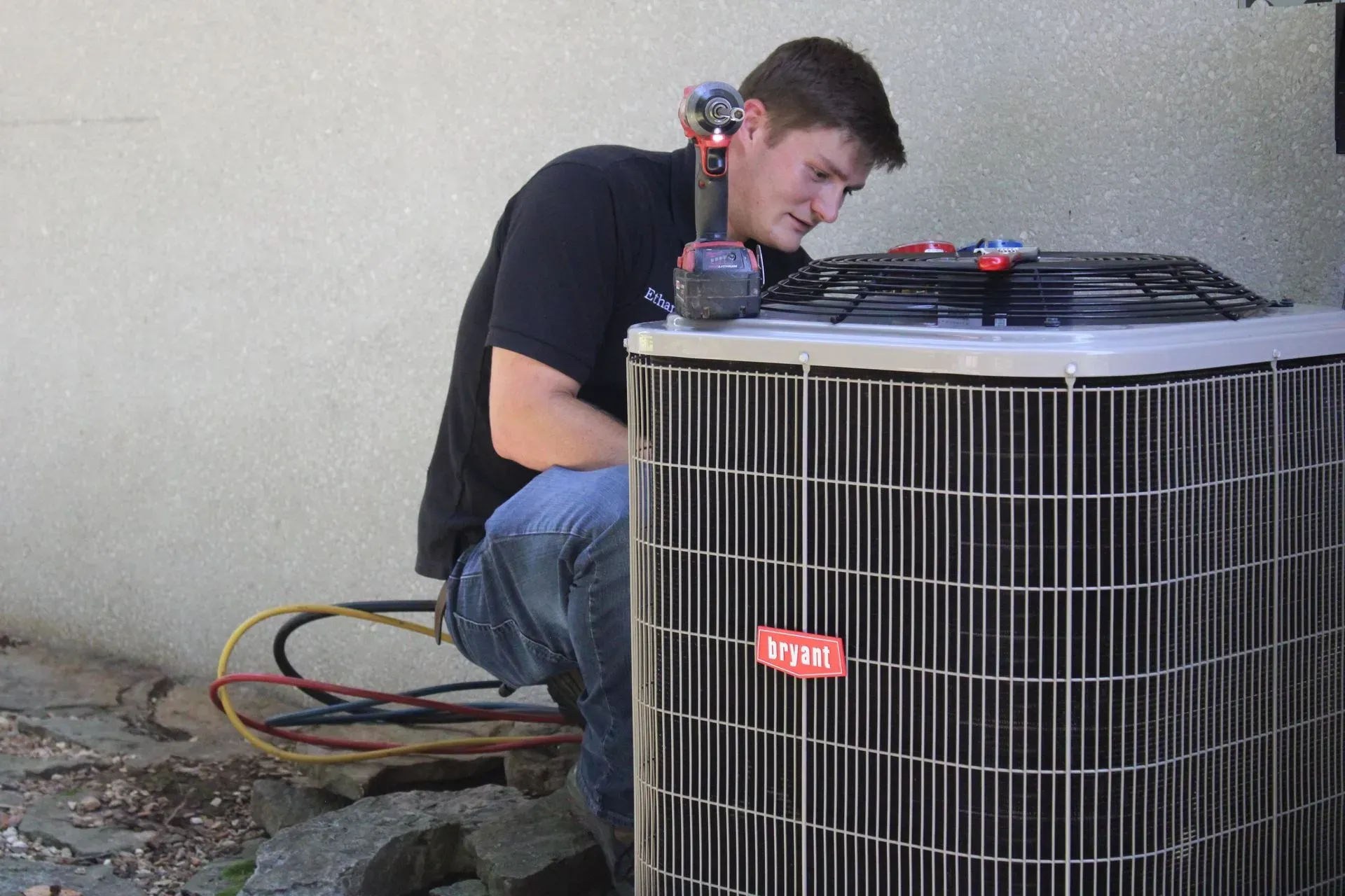 A man is working on an air conditioner outside of a building.