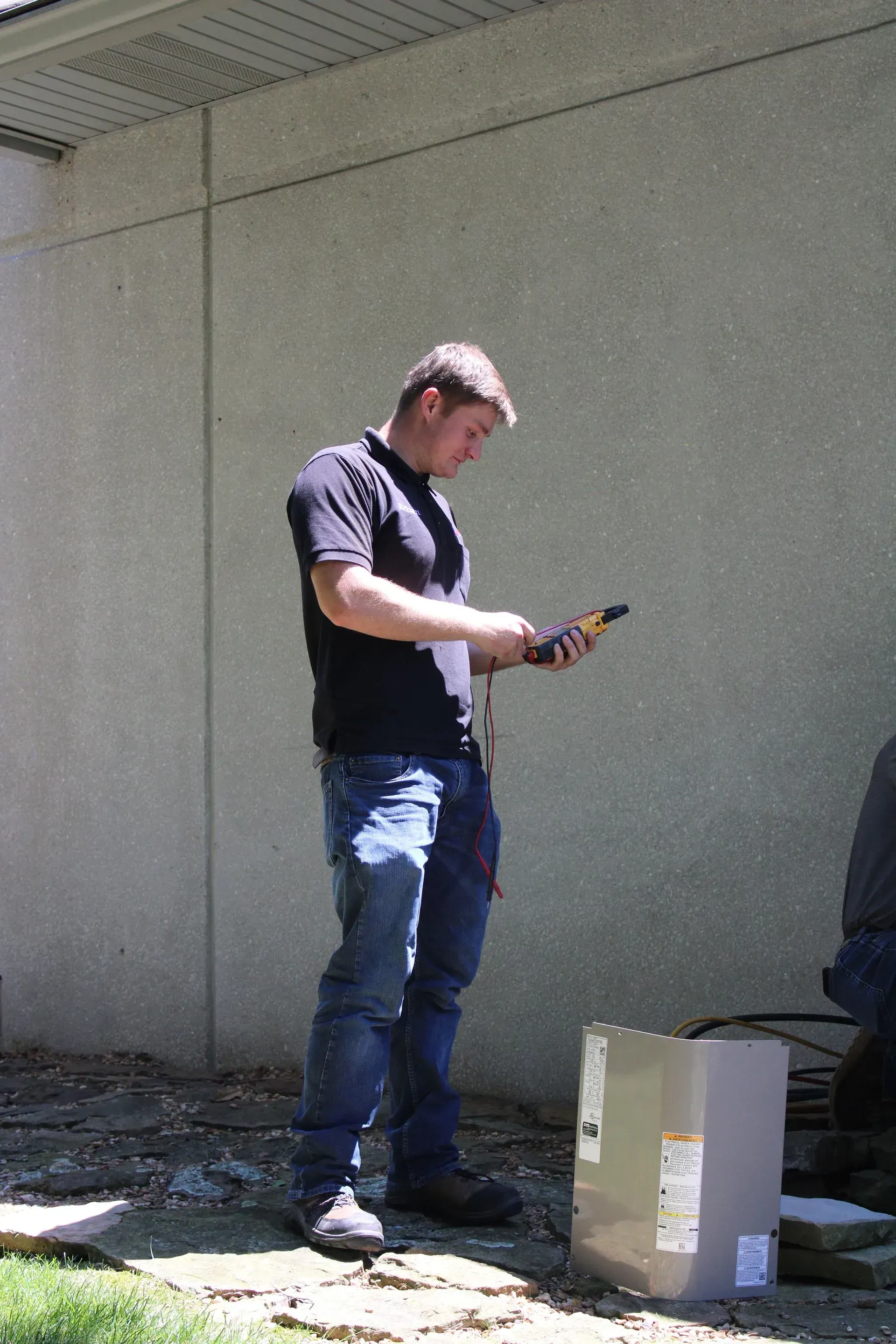 A man is standing in front of a building looking at a cell phone.