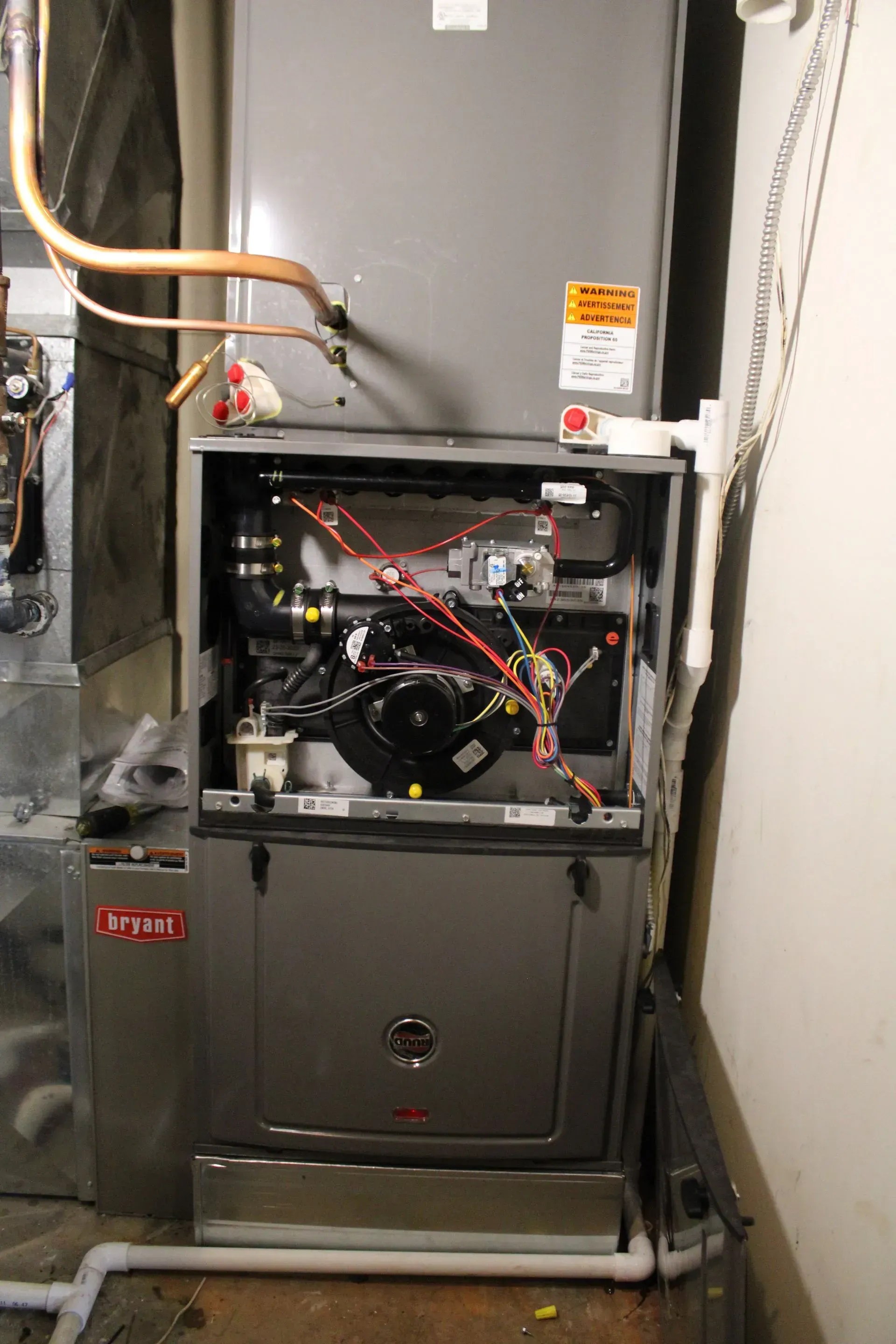 A gray air conditioner is sitting in a room next to a wall.