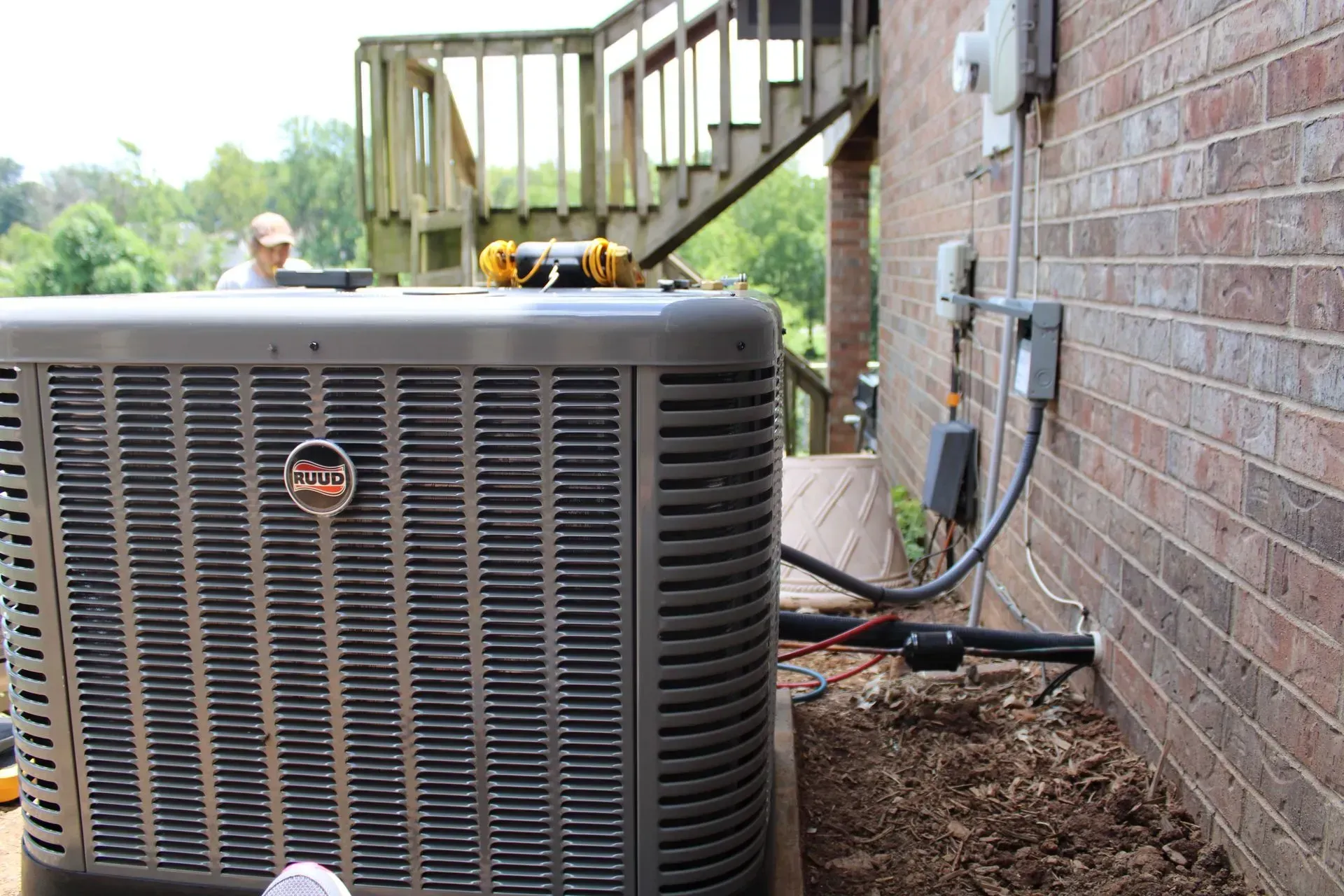 An air conditioner is sitting on the side of a brick building.