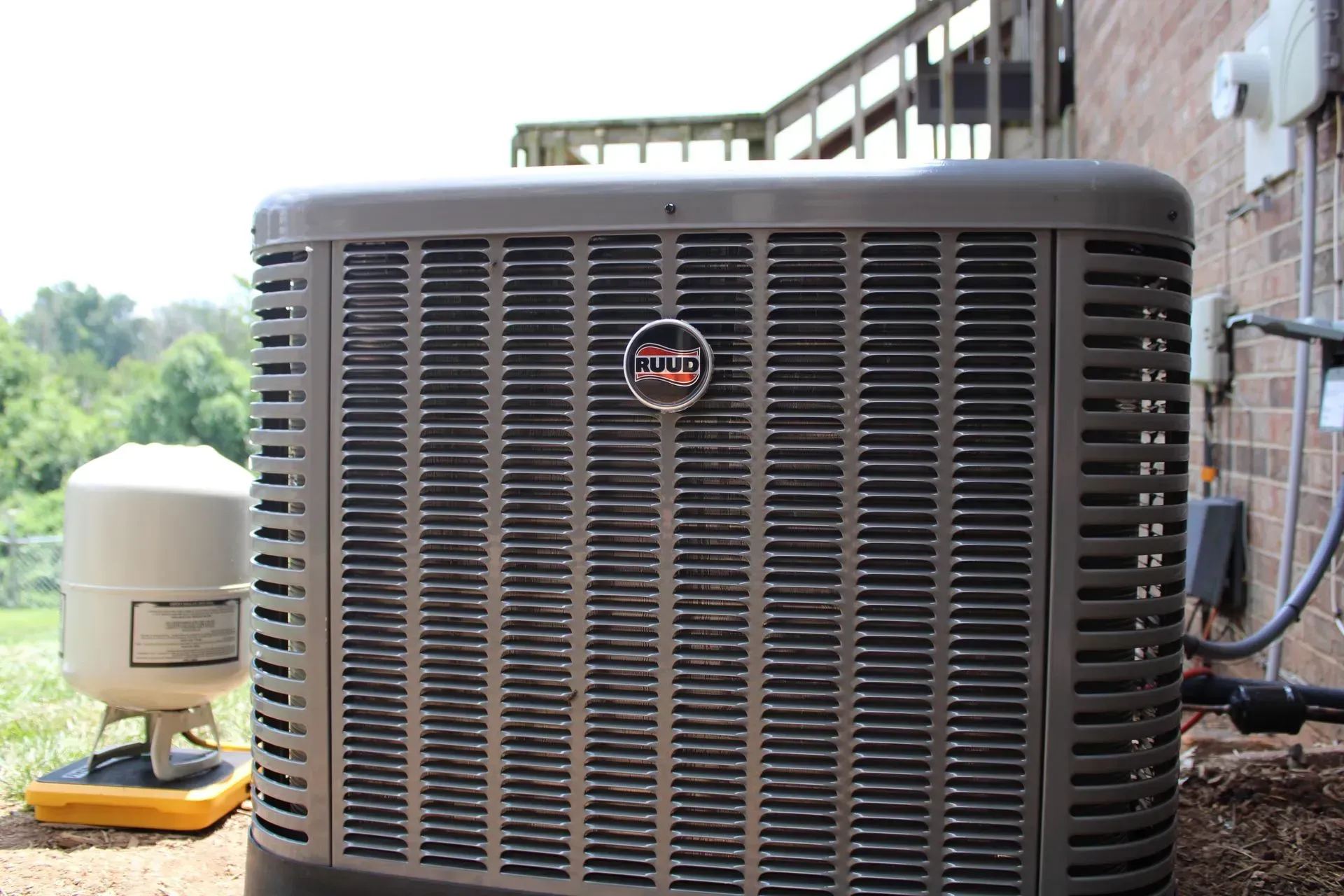 A large air conditioner is sitting on the side of a brick building.
