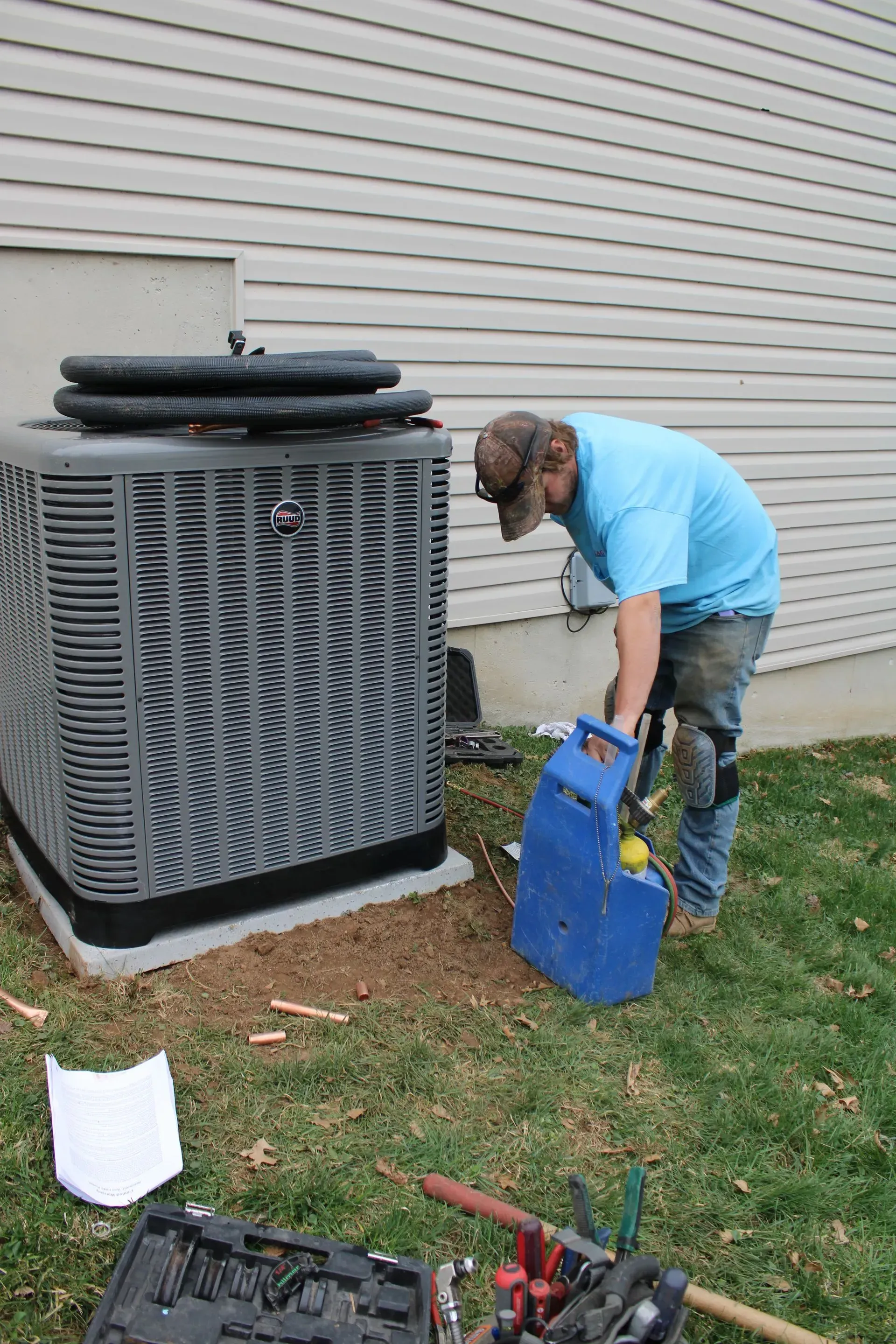 A man is working on an air conditioner outside of a house.