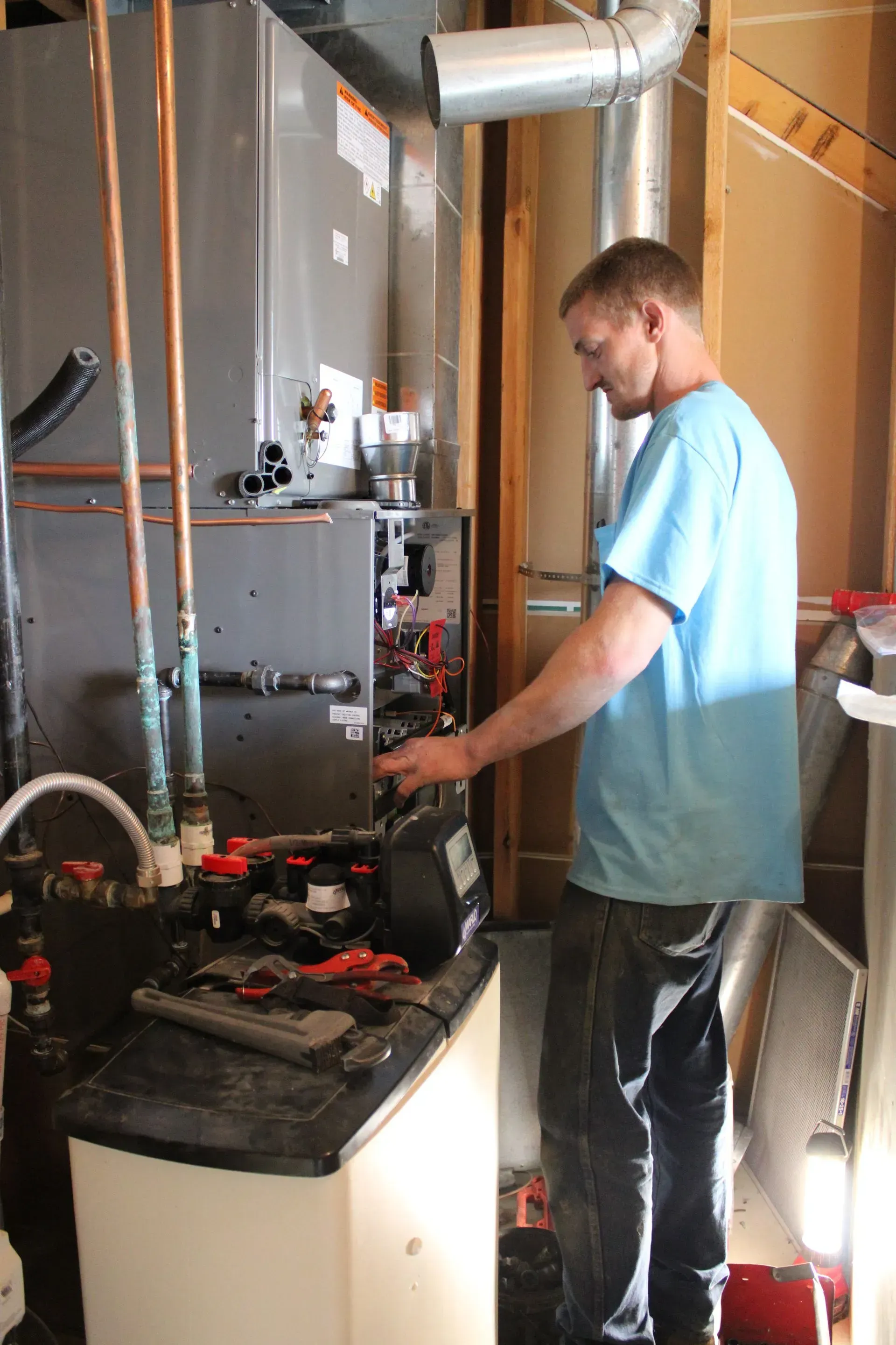 A man in a blue shirt is working on a heating system.
