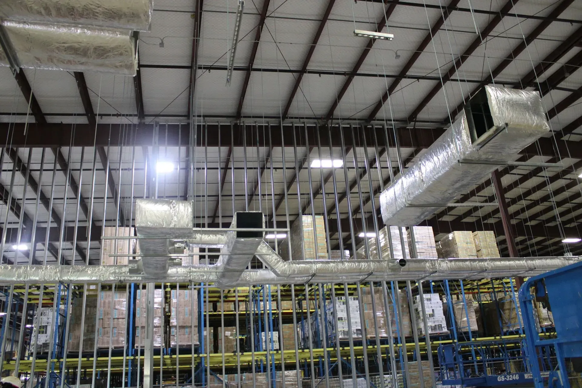 A large warehouse with a lot of pipes hanging from the ceiling.