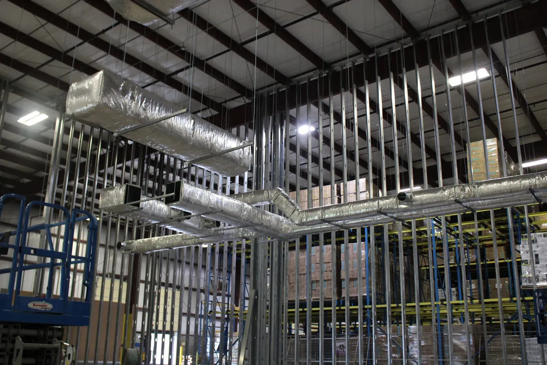 A warehouse under construction with a lot of pipes hanging from the ceiling.