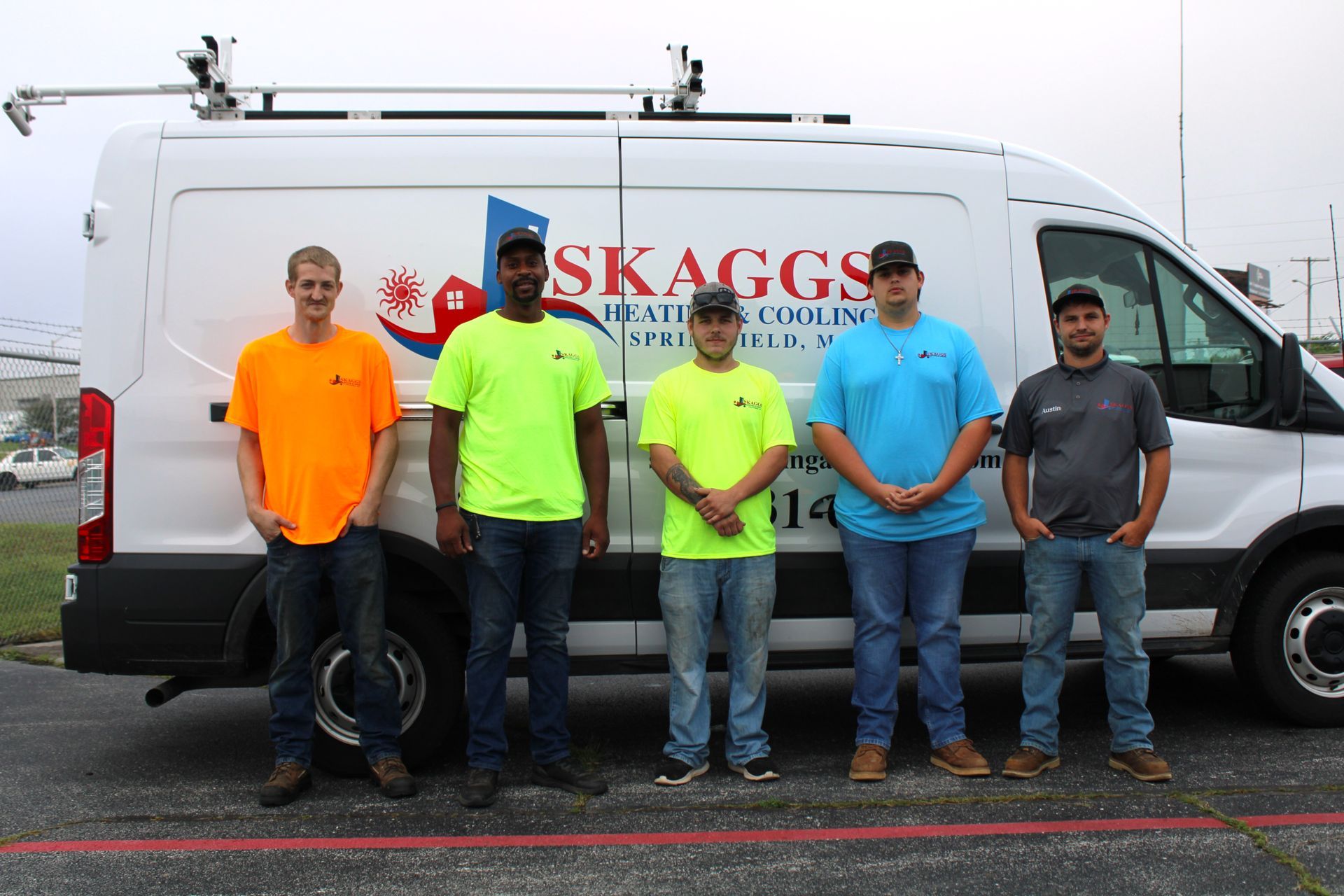 A group of men are standing in front of a skaggs van.