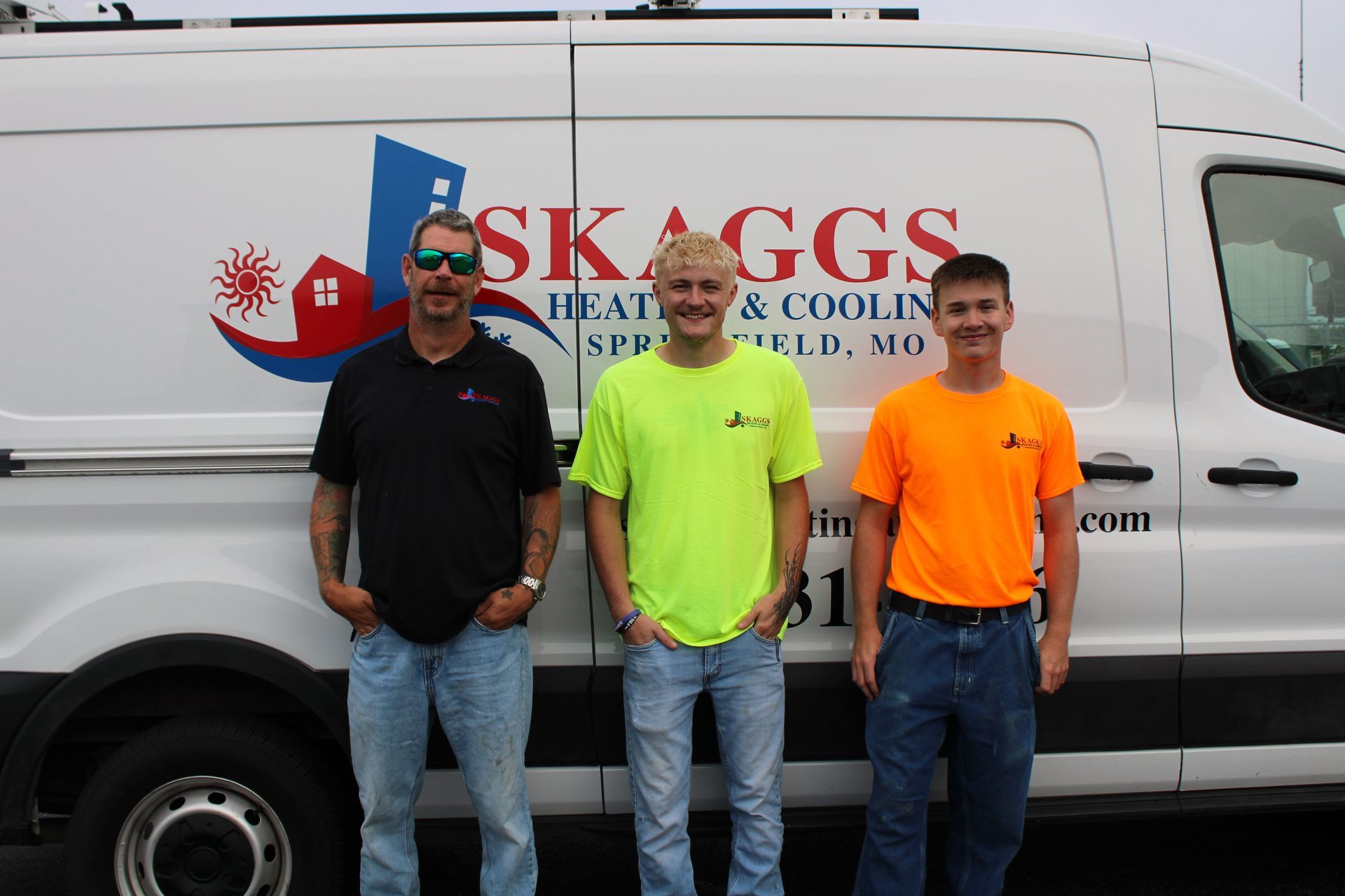 Three men are standing in front of a skaggs van