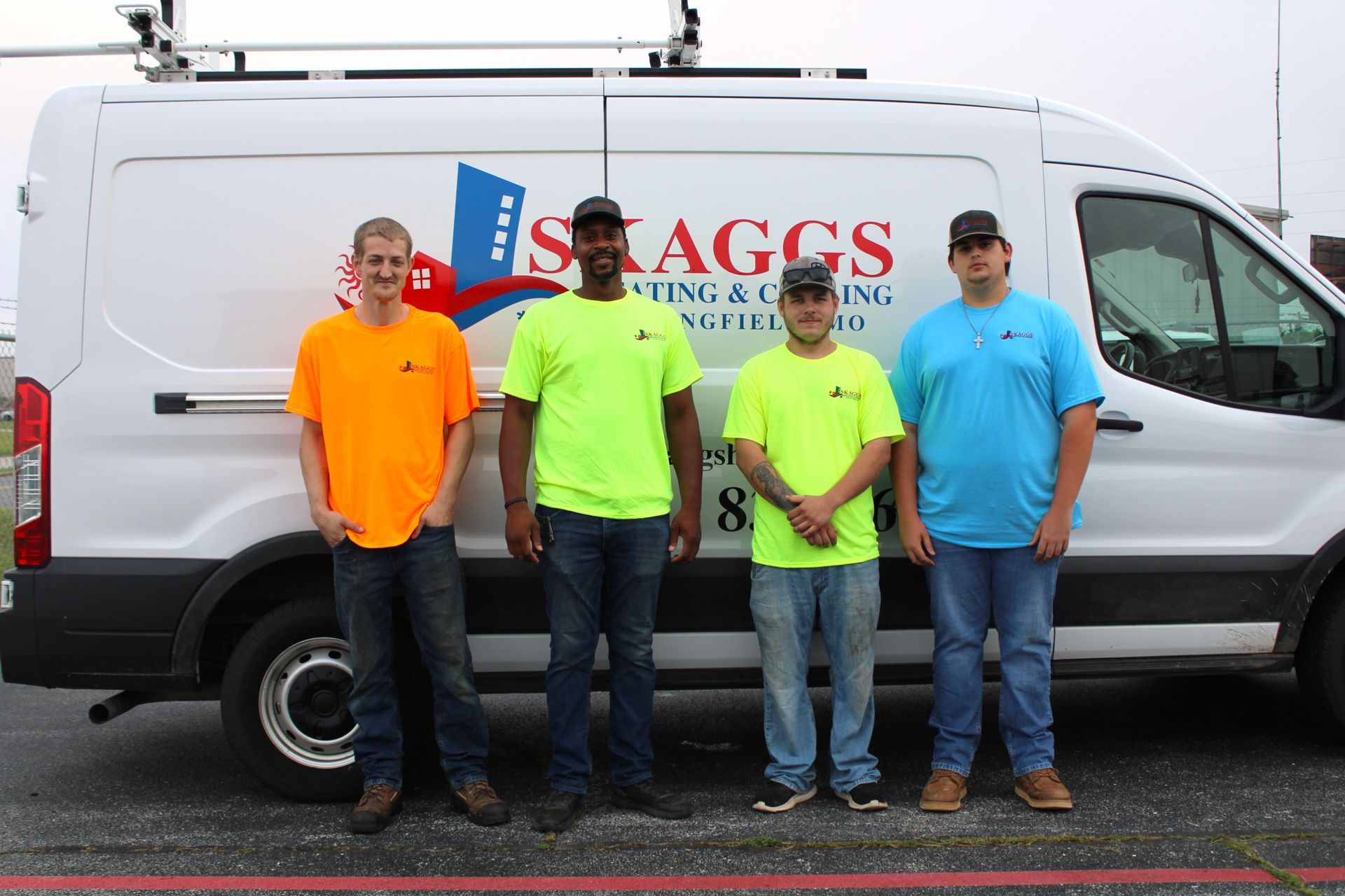 A group of men standing in front of a van that says skaggs