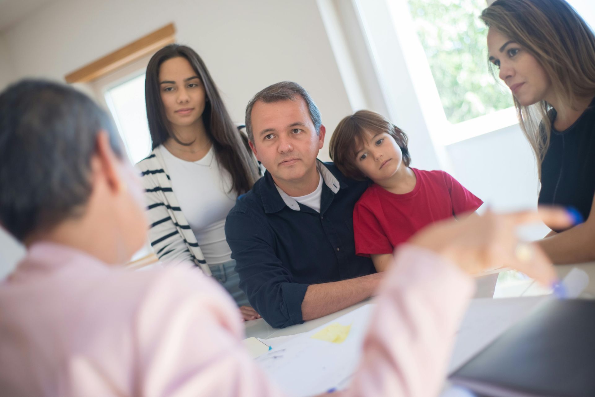 Family in discussion with a person, indoors.