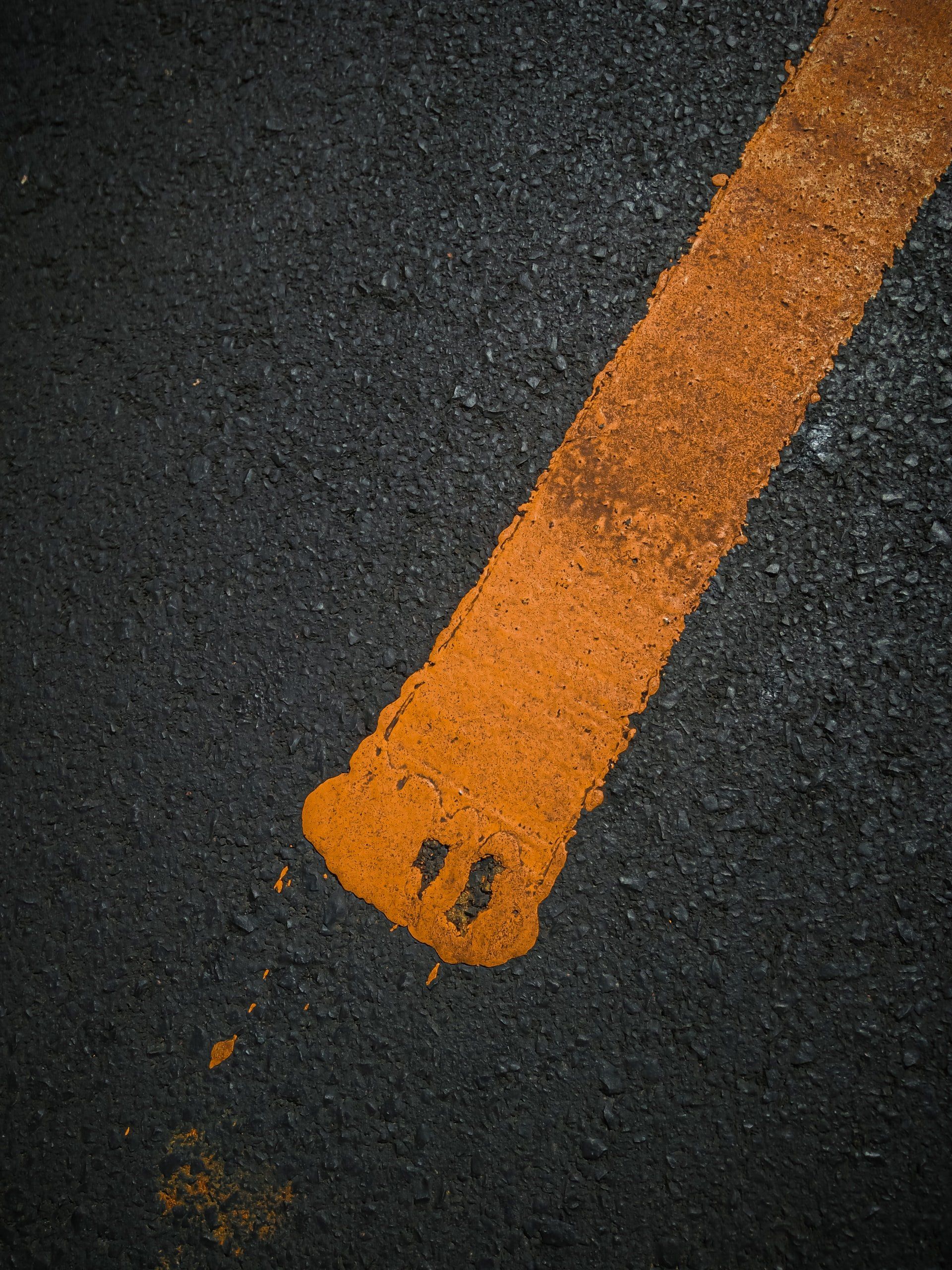 Rich, black asphalt with a faded painted yellow line.