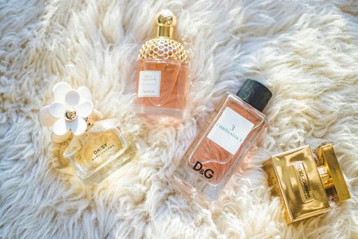 Three bottles of perfume are sitting on top of a fluffy blanket.