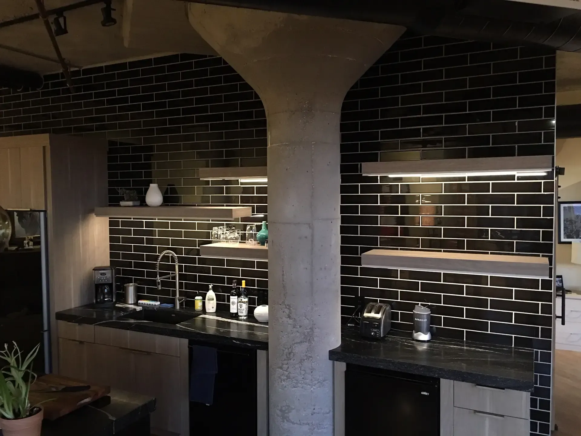 A kitchen with black tiles and a brick wall