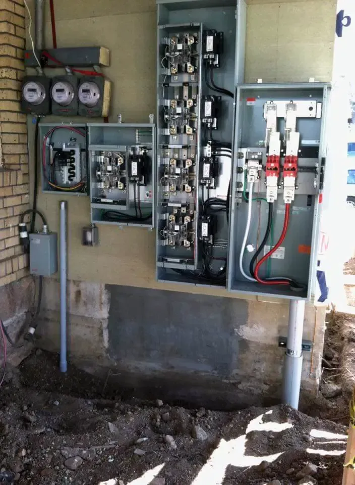 A large electrical box is sitting on the ground next to a brick wall.