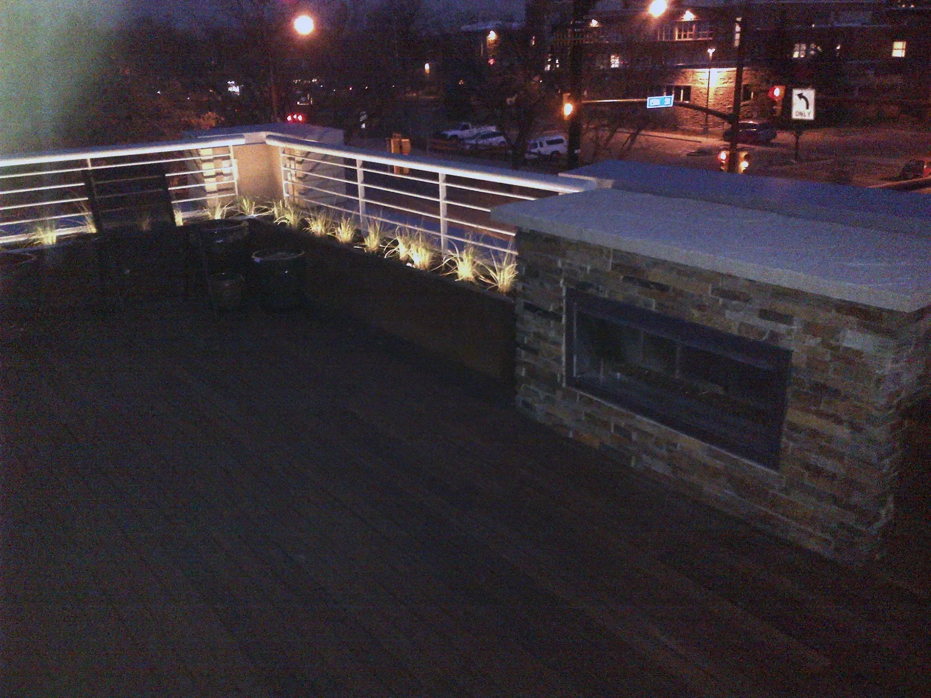 A balcony with a fireplace and chairs at night