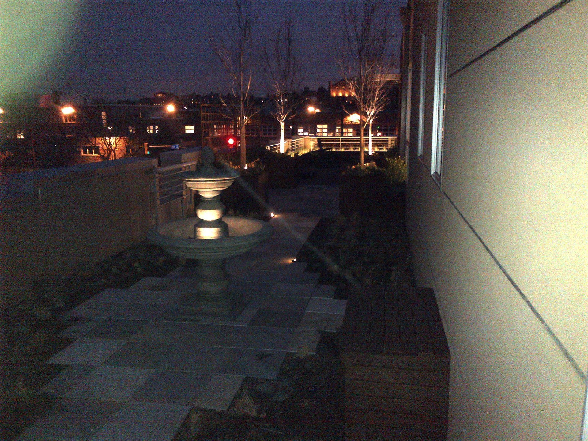 A fountain is lit up at night in front of a building