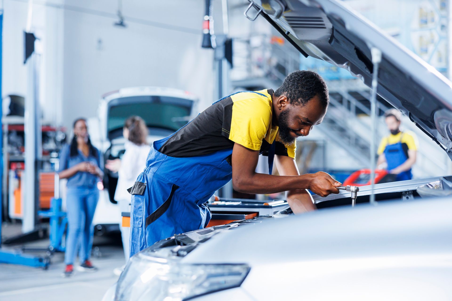 A man is working on the engine of a car in a garage.