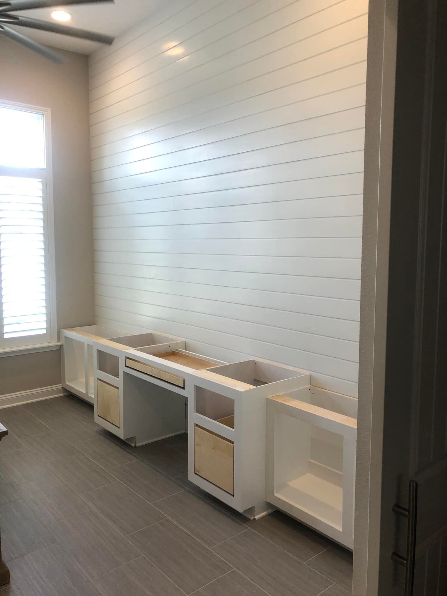 A room with a white wall and a desk in it.