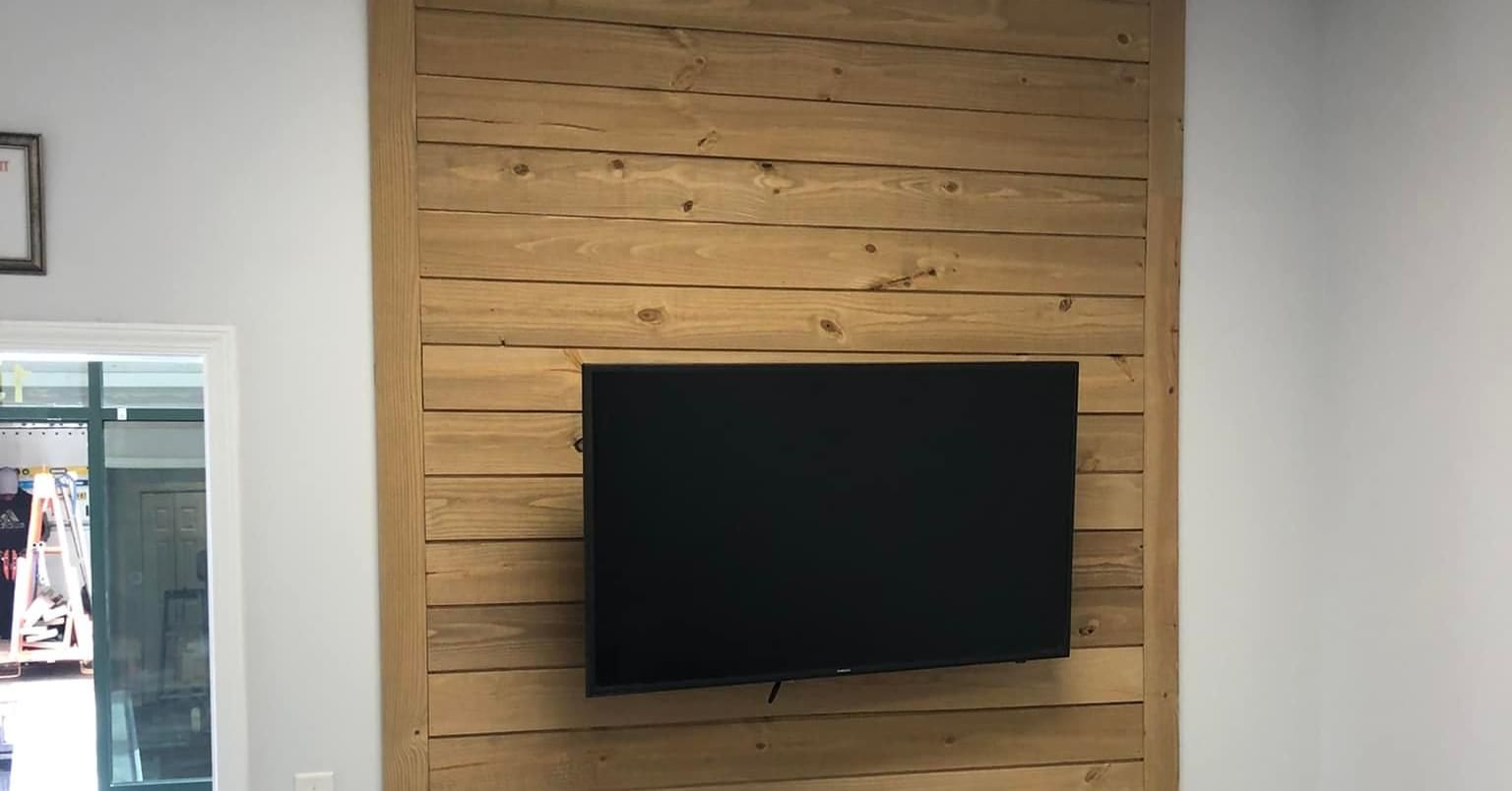 Television mounted on a wooden plank wall. The surrounding walls are white.