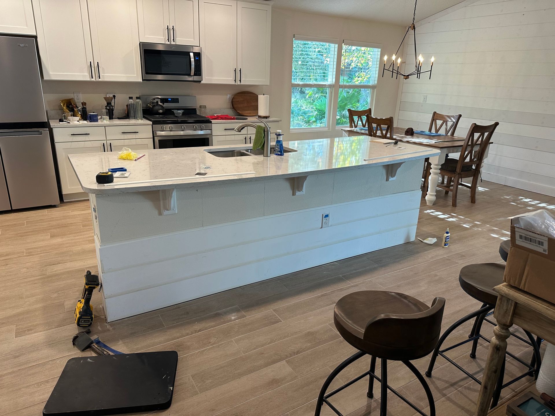 Kitchen with white cabinets, stainless steel appliances, an island, and a dining table.
