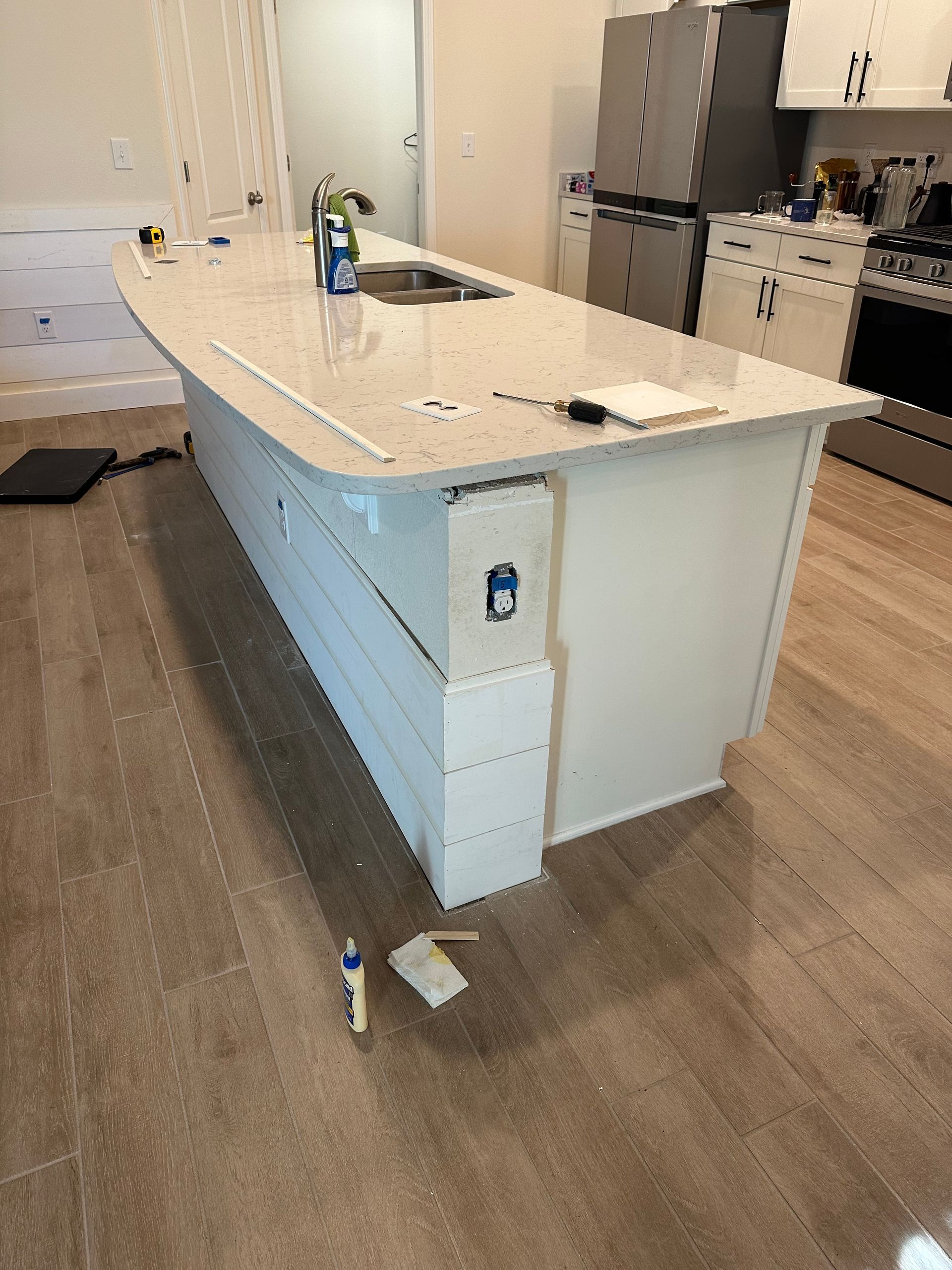 White kitchen island with a light-colored countertop; wood floor.