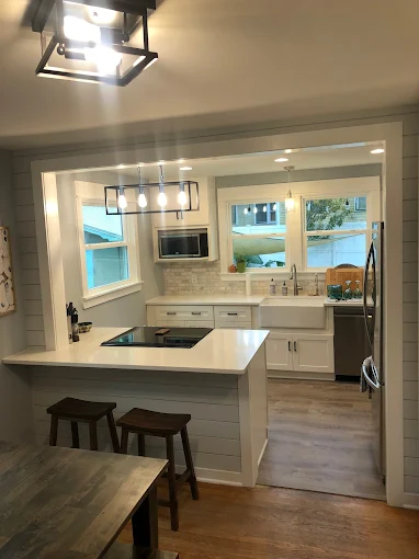 Kitchen with white cabinets, stainless steel appliances, and a light-colored countertop, with bar seating.
