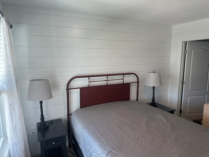 A room with a white wall and a desk in it.