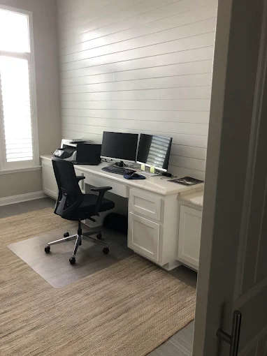 A room with a white wall and a desk in it.