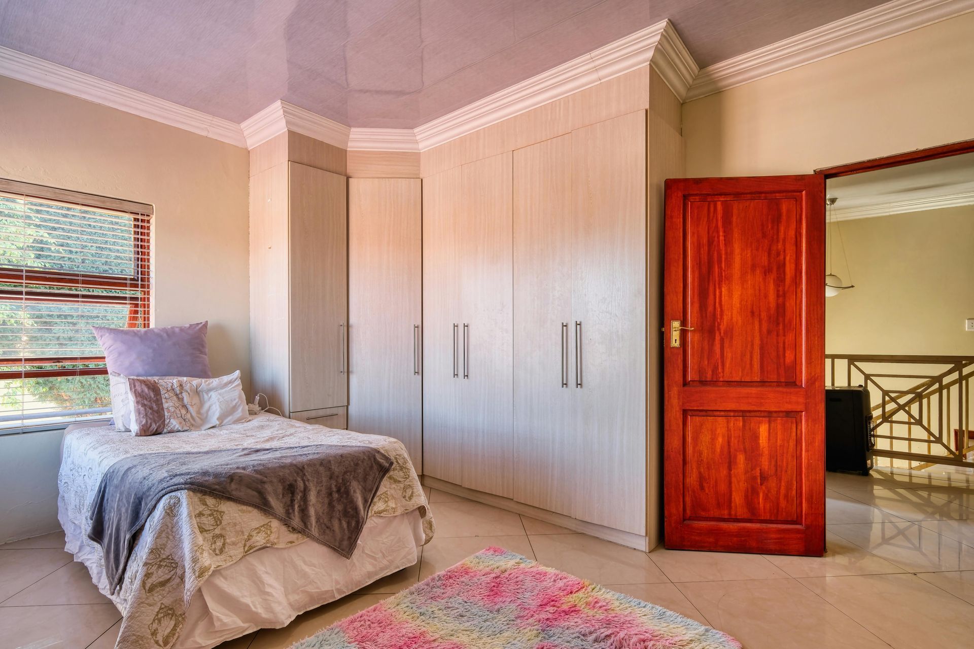 A bedroom with a bed and a red door and crown molding
