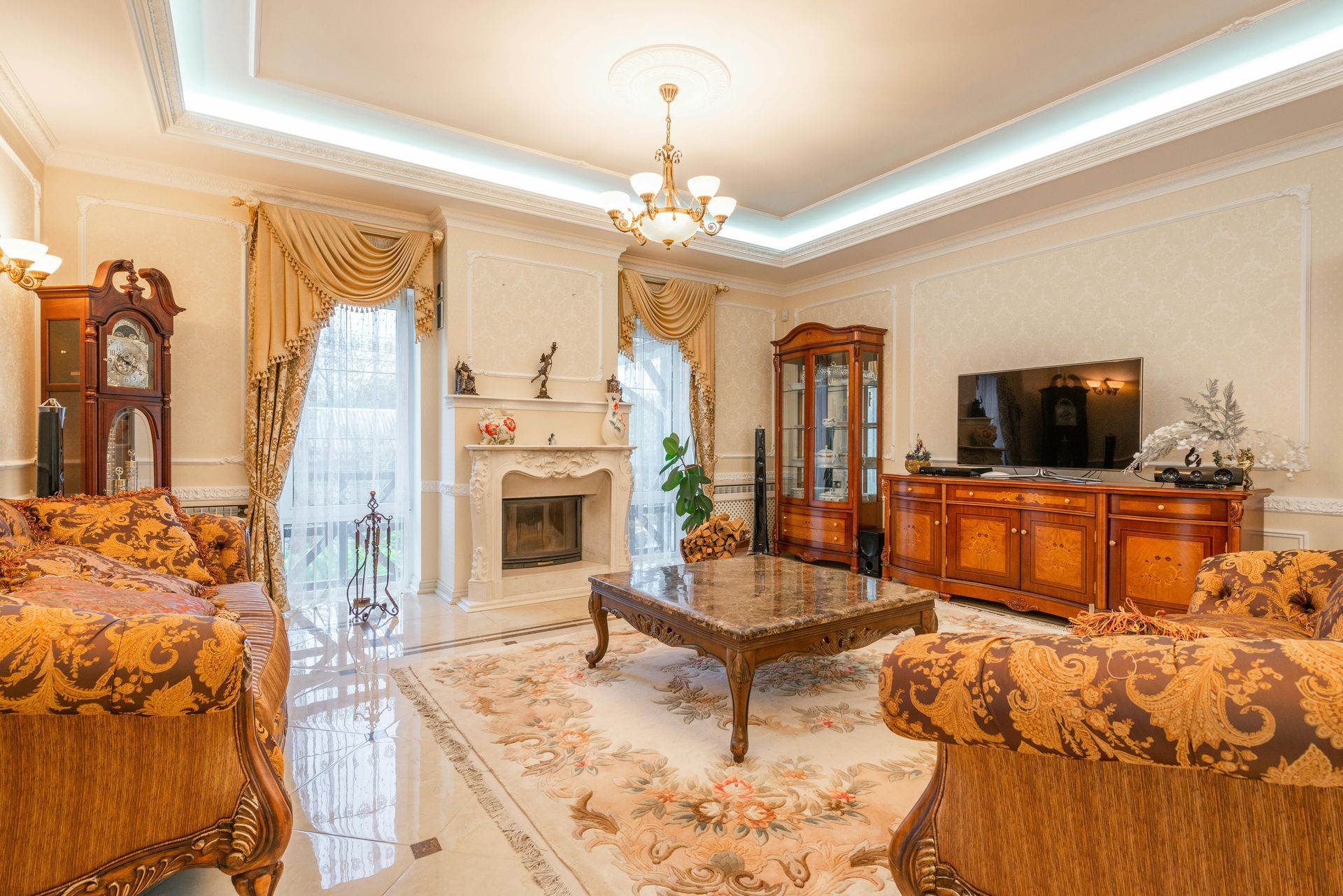 A living room filled with furniture and a fireplace with elegant crown molding that has lighting installed