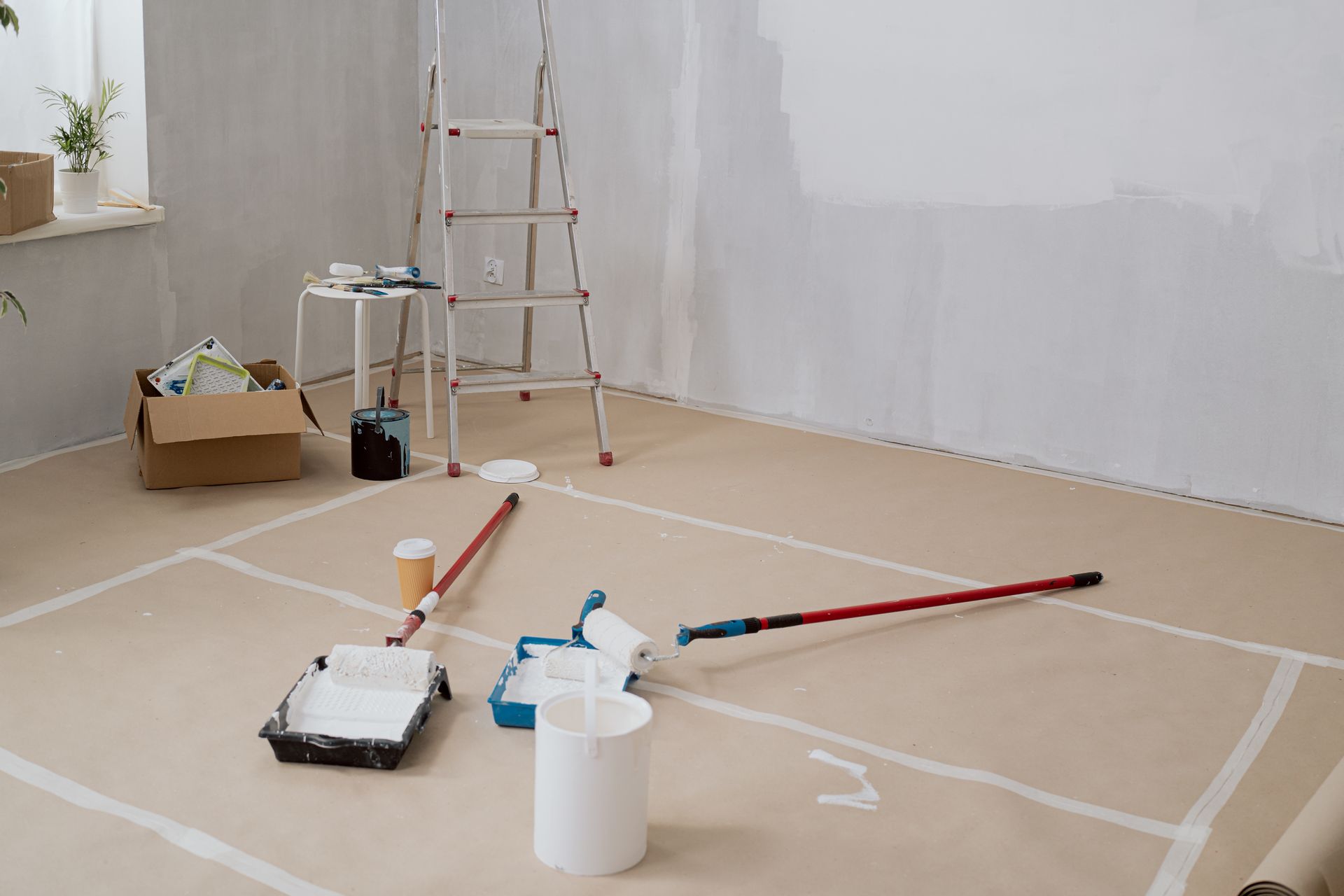 A room is being painted with paint rollers and a ladder.