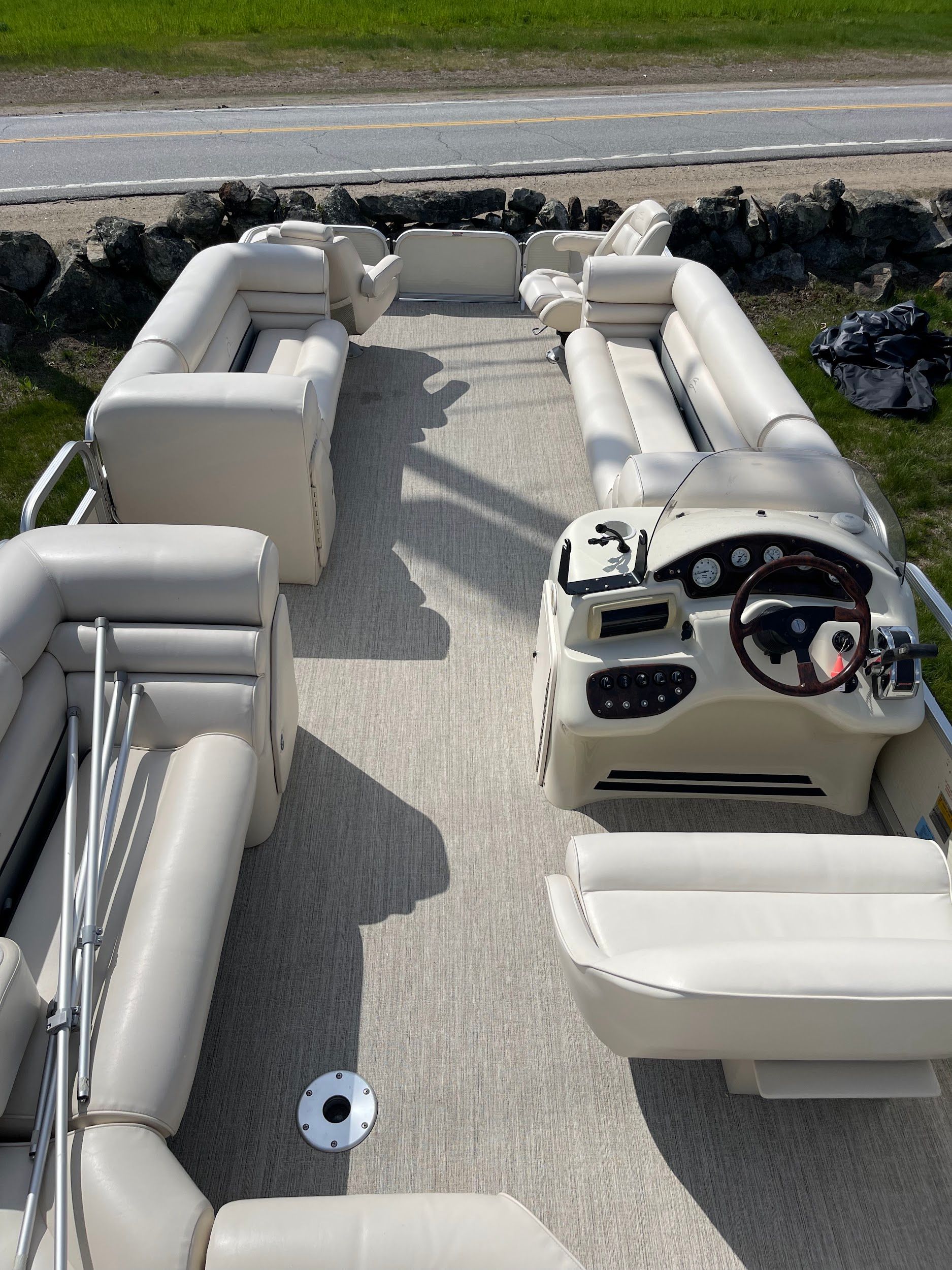 The inside of a pontoon boat with white seats and a steering wheel