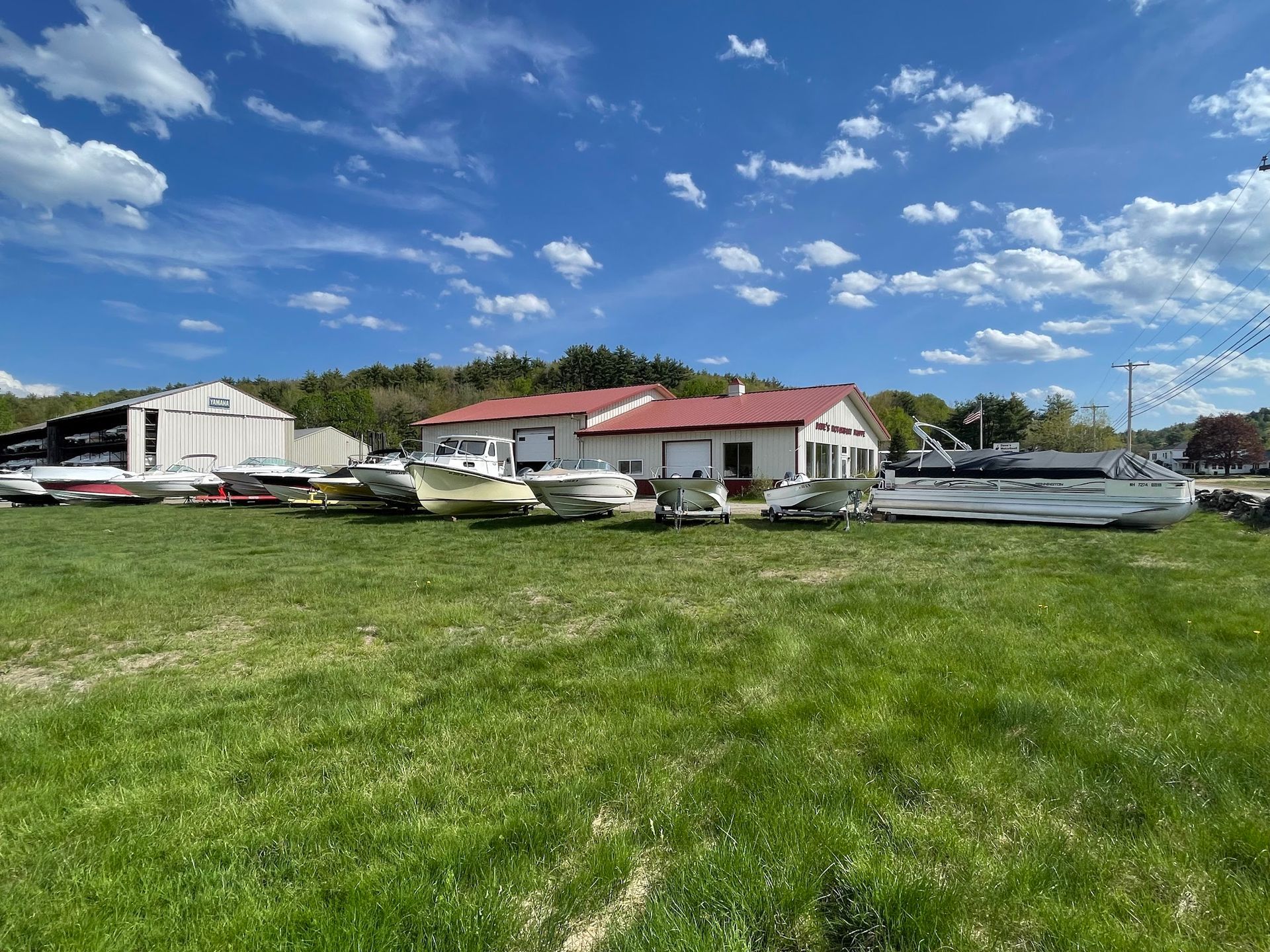 A row of planes are parked in a grassy field in front of a building.
