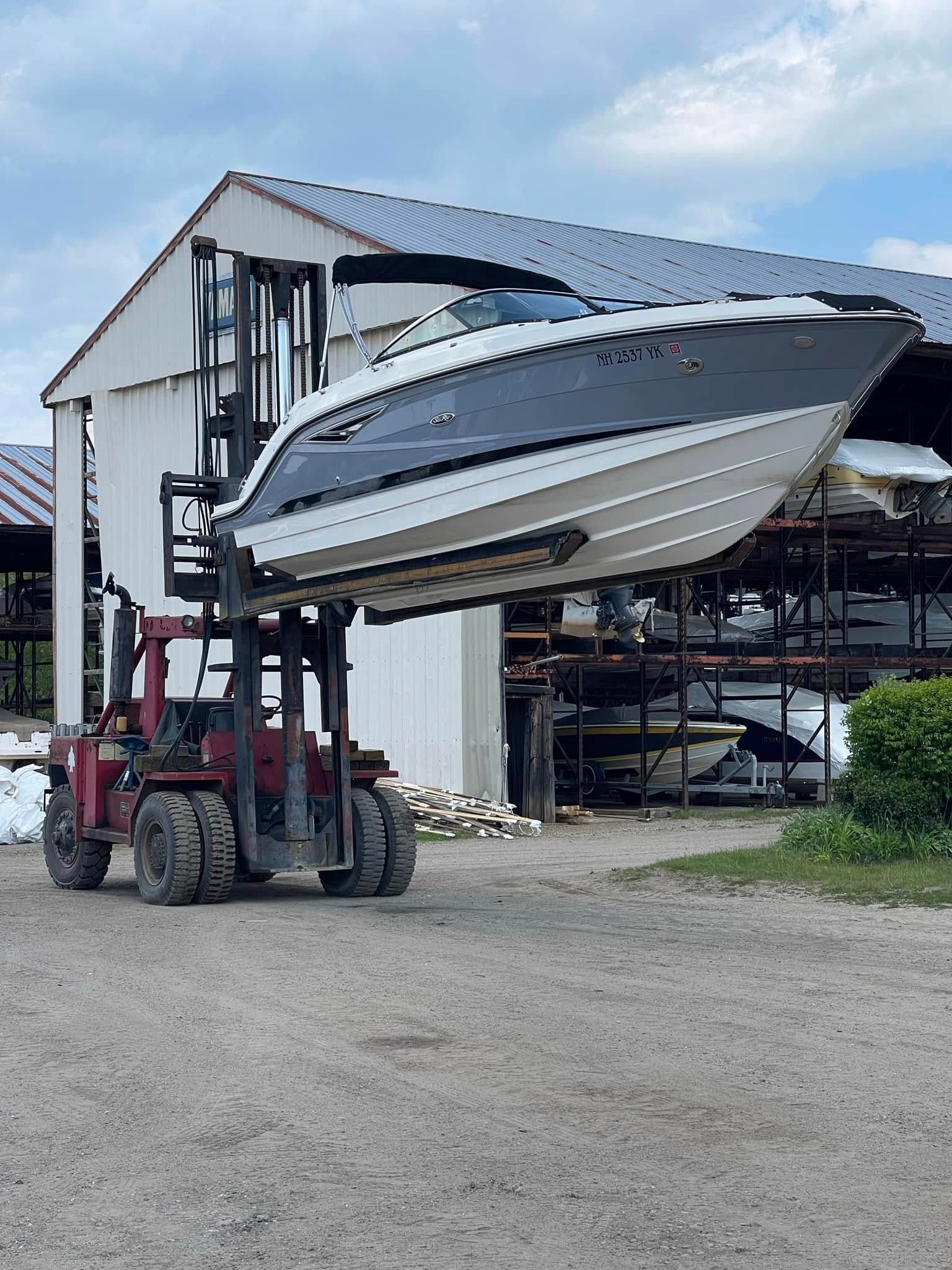 A boat is being lifted by a forklift into a building.