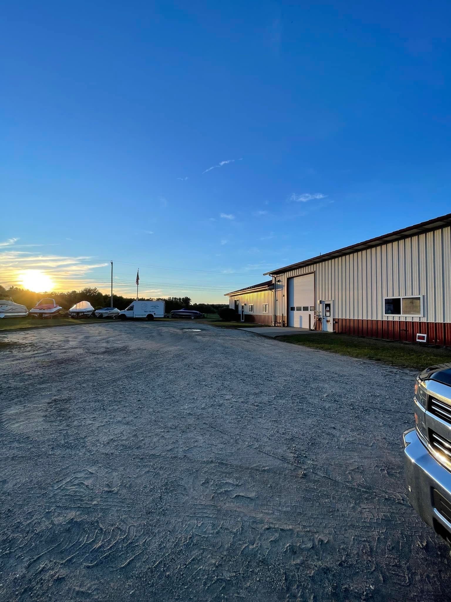 A truck is parked in a gravel lot in front of a building.