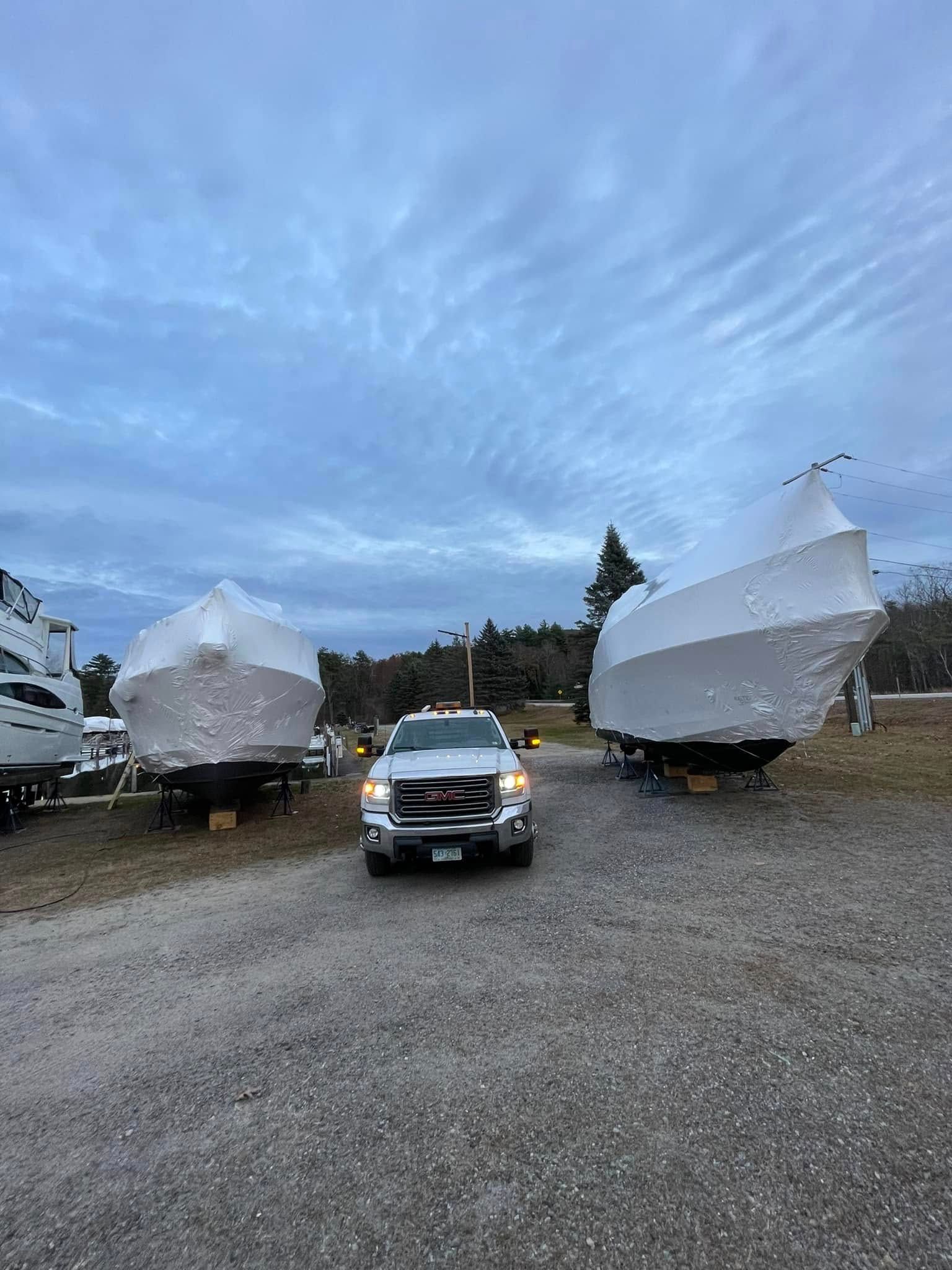 A truck is parked in front of a row of covered boats.