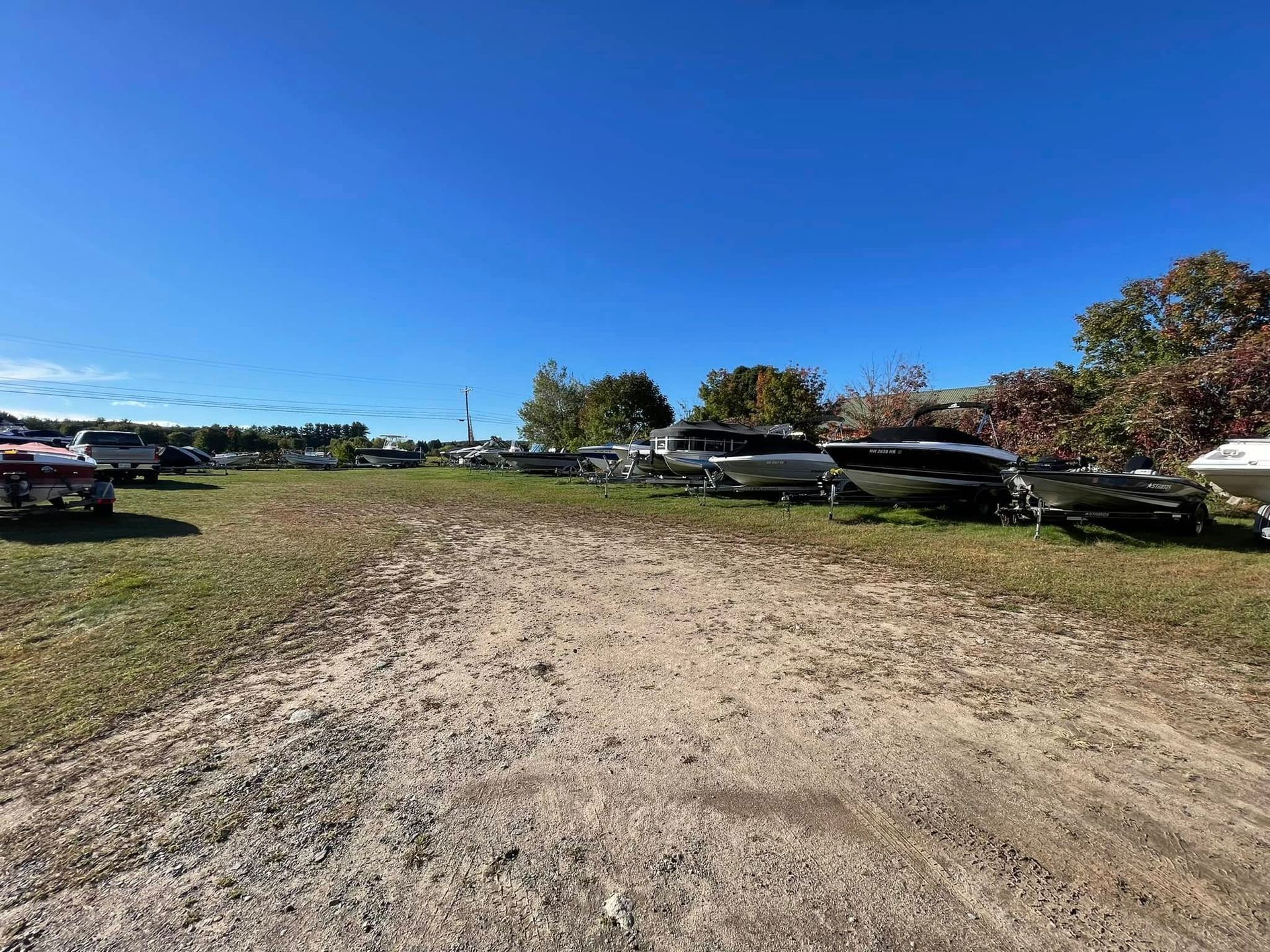 A lot of boats are parked in a dirt lot.
